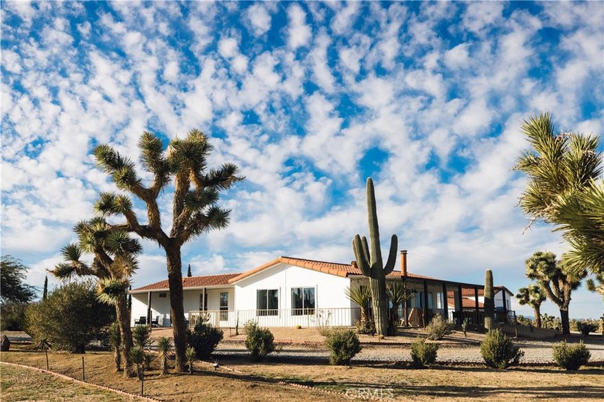 Calling all cowboys—here’s your chance to live out your desert ranch dream. Crazy Heart Ranch blends rustic charm with modern comforts on 5 fully fenced acres, dotted with Joshua Trees and Saguaro cactus, and framed by sweeping mountain views. This 3-bed, 2-bath fully furnished home is ideal for equestrian or farm living and makes for the most authentic equestrian Airbnb retreat. The open floor plan features a light-filled living area with fireplace, seamless flow to the wraparound porch, and a kitchen that opens to dining and living for easy entertaining.



Outdoor living defines the property, with multiple spaces designed for relaxation and gathering. A sprawling three-sided wraparound porch provides year-round reprieve—grill and dine in the summer breeze, sip morning coffee while the desert awakens, or gather at dusk as the skies come alive with color. A jacuzzi, cowboy dipping spas, outdoor shower, and firepit set the stage for starlit evenings under the Hi-Desert’s famed dark skies. Ride directly from the property into open desert trails, or simply watch the shifting light move across the surrounding mountains from your own private sanctuary.



Equestrian facilities include a Western-style tack shed, two stalls, and a riding arena, while a 3-car garage plus RV garage with hookups expand storage and flexibility. Upgrades throughout, central heat/AC, solar to offest electrical $320/mo. and thoughtful design ensure comfort in every season.



Beyond the property, inspiration and adventure abound. Pipes Canyon, with its endless hiking and riding trails, lies just minutes away. A short 20-minute drive delivers you to the historic western town of Pioneertown, home to world-famous entertainment and dining at Pappy & Harriet’s. La Copine, a local culinary landmark, is less than 10 minutes from your gate, and the entrance to Joshua Tree National Park is only 20 minutes away.



Whether as a primary ranch home, short-term rental investment, or equestrian retreat, Crazy Heart Ranch offers an unmatched blend of privacy, lifestyle, and proximity to the very best of the Hi-Desert.