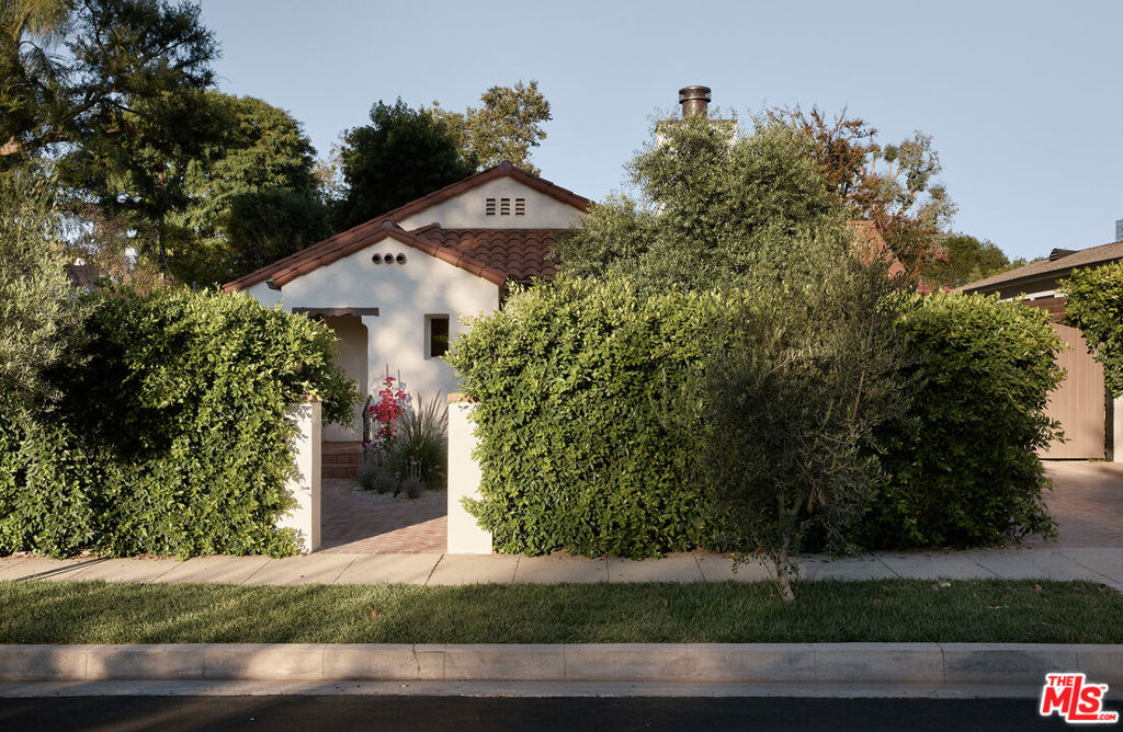 Presenting an adorable 1926 Spanish, fully renovated and updated with fine materials and on-trend finishes throughout and set behind lush privacy hedges. A brick pathway leads past carefully selected drought-tolerant landscaping to the front entry. Inside, the living room retains its original charm with a stucco fireplace, arched ceiling and doorways, and a large picture window that frames the garden outside. The dining room has a French door opening to the side patio to optimize indoor-outdoor entertaining flow, adjacent to the expertly appointed, immaculate kitchen with organic finishings, state-of-the-art range with hood, shimmering backsplash, breakfast nook, and pantry with built-ins. The primary suite is spacious and continues the home's delightful design theme, complete with French doors and side patio plus a bathroom with a dual-sink vanity, separate rainwater shower, and soaking tub. Secondary bedrooms and bathrooms are also well-appointed. In the backyard are a variety of lounging areas, patios, gardens, a calming water feature, fire pit, grassy lawns, and outdoor dining for serving al-fresco bites on warm summer evenings. There is also a one-bedroom ADU for guests and generating additional income as well as a converted flex space currently used as a gym but can also serve as an office, artist's studio, meditation room, and more. Welcome to this ideal Studio City location close to Universal City, schools, parks, and studios, all just moments to the restaurants along Ventura Boulevard plus The Shops at Sportsmen's Lodge, anchored by Erewhon and Equinox.