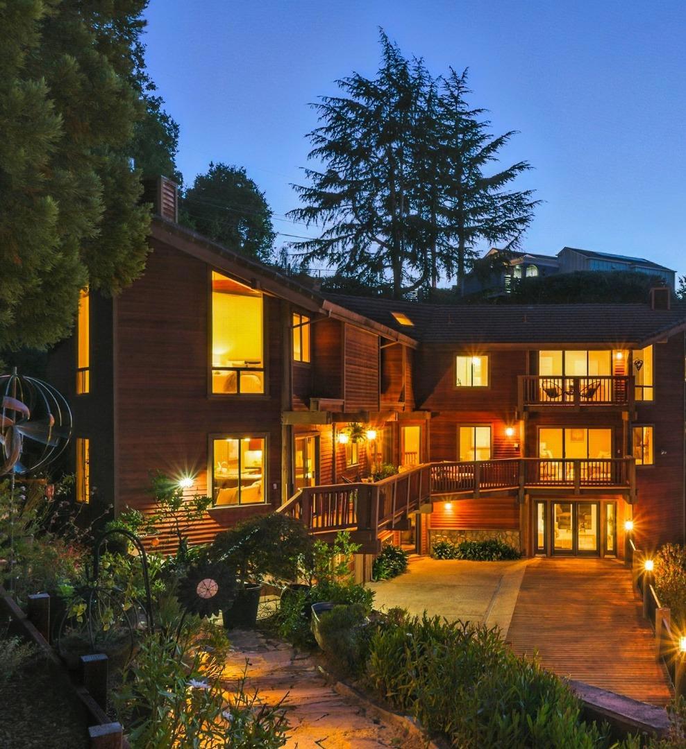 A Tahoe-like retreat in the heart of Silicon Valley, featuring stunning views, custom design, and ample space for family life or entertaining. Tucked away on a scenic mountain road and surrounded by mature trees, this custom-built mountain-style home blends retreat-like privacy with everyday convenience, just minutes from downtown San Carlos and Belmont. Built in 1993, the residence is designed to capture natural light throughout the day, from sunrises to glowing sunsets, with views stretching to the Bay Bridge, San Francisco skyline, and 4th of July fireworks. The floor plan flows seamlessly from room to room, creating an inviting atmosphere for both daily living and gatherings. The modern kitchen features dual ovens and dishwashers, ideal for hosting or family meals. Multiple living areas include a cozy family room, generous bedrooms, and a convenient laundry. Step outside to enjoy wraparound decks and balconies that bring the outdoors in, perfect for morning coffee or sunset dinners. A garden, dedicated wine storage, and private spaces for entertaining make this home as functional as it is unique. Whether sharing moments around the fireplace or enjoying the serenity of the wooded surroundings, this home offers a rare combination of mountain retreat lifestyle and Silicon Valley