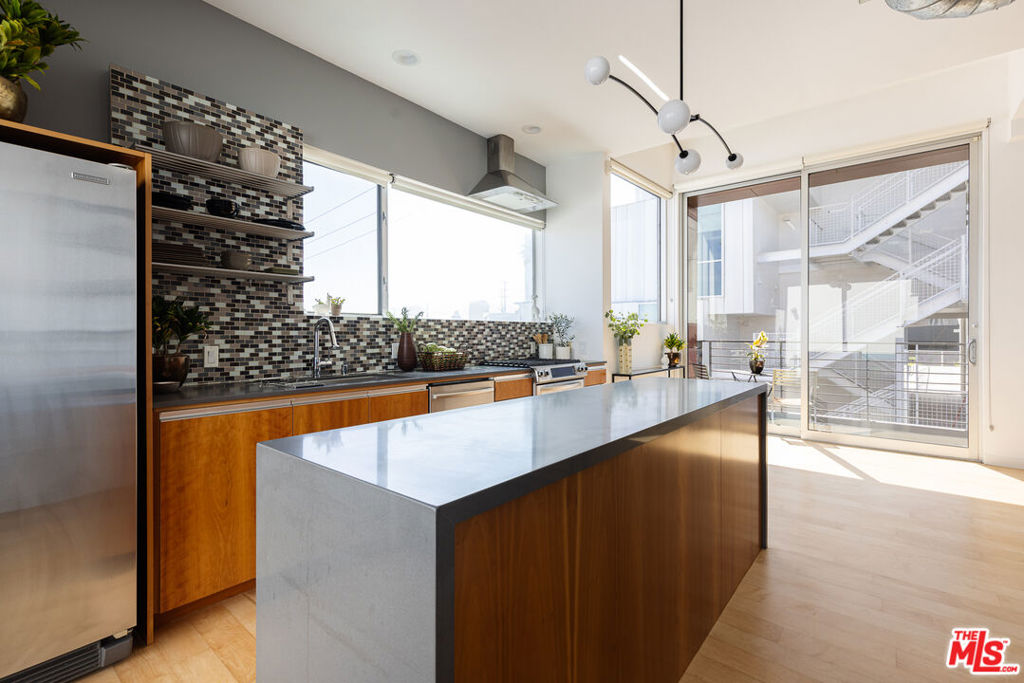 Hacienda Lofts is an impeccable boutique collection of 8 elite luxury condominiums. Located in prime West Hollywood, this architecturally-significant townhouse-style penthouse loft with superb views boasts an open and airy layout that could easily be converted into 2 bedrooms plus 2 bathrooms. Designed by celebrated local architect Ric Abramson, FAIA, this rear-corner unit offers enviable privacy and tranquility, featuring impressive windows on all sides, only one shared wall, and breathtaking views of the Hollywood Hills and city below from every angle. Bathed in natural light, this unit's highlights include maple hardwood floors, soaring ceilings, recessed lighting, and plentiful closet/storage space throughout. A seamless floorplan guides you through a smart, modern kitchen that boasts refined stone countertops and higher-end stainless steel appliances, to two separate outdoor spaces off the kitchen area - one spacious lounging deck with recently redone flooring and one relaxing balcony that is perfect for your morning coffee. The open living and dining areas are tastefully decorated with modern chandeliers, custom window treatments from The Shade Store, and a welcome guest bathroom. The lower level's main attraction is a sumptuous primary bedroom suite, with floor-to-ceiling windows, custom window treatments, and a calming, spa-like bathroom with natural limestone finishes, separate standing shower and deep soaking tub.The versatile secondary bedroom space can serve as a stylish home office or comfortable guest room/family room. You'll appreciate a dedicated laundry room/utility room and two tandem parking spaces in the secure subterranean garage, plus a deeded oversized 4' X 6' storage locker in the garage. A total of three private balconies highlighted by a spacious 114 SF rooftop terrace offer the pinnacle in indoor-outdoor living, perfect for sunset cocktails and entertaining or weekend lounging with plenty of space to unwind. This distinctive building is a modern interpretation of classic West Hollywood courtyards, with a vertically stacked design that enhances light, privacy and architectural impact; no long hallways - just smart, efficient, vertical living in a peaceful, environmentally-friendly, design-forward environment. Hacienda Lofts is positioned perfectly just blocks from the renowned Sunset Strip, Sunset Plaza and vibrant Santa Monica Blvd. and sports a desirable walk score of 91 - you'll be mere moments from both incredible destination restaurants and noteworthy neighborhood hangouts, including Connie & Ted's, Tower Bar, Jinpachi, Daughter's Deli, Sunset Marquis, Alba, DiDi, Ggiata Delicatessen, Katana Robata, Madre, Pura Vita, Saltie Girl, Tail O' The Pup, and Traktir, plus world-famous nightlife just a stone's throw away. An exceptional opportunity awaits!