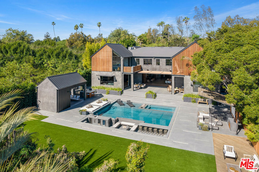 Gated contemporary farmhouse compound on a 20,000 SF flat lot and tucked away in the ultra-exclusive Bel Air enclave. Pass through the fire-lined walkway & bridge to jaw-dropping interiors with dark wood features, petrified Elm floors, poured concrete & warm tones throughout. The details and fit & finish are to the highest standards. Natural light pours in from every room and formal living & dining open to a backyard oasis including pool, spa, sunken bar, BBQ, lush lawn, 6 fire pits and an outdoor screening area. Lavish primary suite fit for a king with fireplace centerpiece, vaulted ceilings, closet, bathroom and private balcony. 4 additional en suite bedrooms and pet spa upstairs. Take the elevator to the lower level entertainment lounge equipped with state-of-the-art amenities including bar, wine room, table tennis, fitness room and theater. This estate combines flawless design & world-class luxuries to live & entertain at your own private sanctuary in the best location in LA.