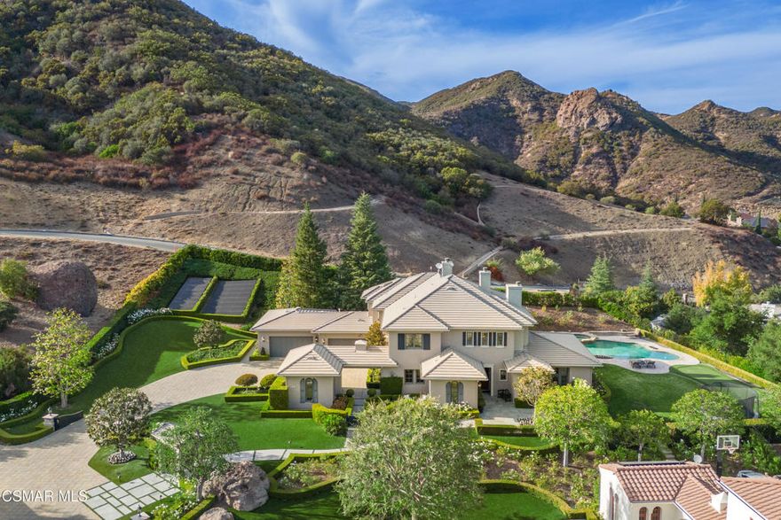 Welcome to an extraordinary privately gated estate in the prestigious Sherwood Country Club. This remarkable property boasts 6,241 square feet of refined living space, featuring 5 bedrooms and 5.5 bathrooms. The main residence encompasses approximately 4,952 square feet, while the luxurious 1,289-square-foot guest house adds versatile living options. Together, they offer an impressive 7-car garage capacity. Nestled at the end of a secluded cul-de-sac, this home is set on an expansive 1.25-acre lot and offers picturesque views of the Sherwood golf course and surrounding mountains. Step into a grand foyer highlighted by a sweeping circular staircase. The main level showcases elegant wood flooring and thoughtfully designed spaces, including a living/game room with soaring beamed ceilings, tall windows, and a grand fireplace. The family room exudes warmth with its cozy fireplace, while the gourmet kitchen delights with two central islands and top-tier Wolf, Sub-Zero, and Miele appliances, perfect for culinary enthusiasts. The upper-level primary suite is a luxurious retreat, offering panoramic views, fireplace, a sitting area with a private balcony, a spa-like bath, and spacious closets. Two additional en-suite bedrooms with generous closets complete the upper level, while a third en-suite bedroom on the main level provides privacy and comfort for guests. The guest house is a retreat of its own, featuring  a media room with a cutting-edge golf simulator, a bedroom and bath, and flexible spaces ideal for an office, studio, or gym. Outside, the expansive grounds are an entertainer's dream, with lush lawns, a sparkling pool and spa, custom fire pit, an outdoor BBQ center and an additional Dog Kennel area. Modern sustainability features include a 40-panel owned solar system powering the entire property and a Hunter Hydrowise irrigation system for efficient water management. This exceptional Sherwood estate offers an incomparable lifestyle!