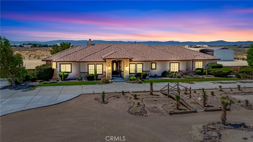 Live the Dream in this Custom Mediterranean Ranch-Style Estate! Set on a Fully Usable 2.52-Acre Lot, this Beautifully Designed Single-Story Home Offers Nearly 3,000 sq ft of Luxurious Living Space with 4 Spacious Bedrooms & 3 Bathrooms. Built in 2008 with No Expense Spared, it Blends Timeless Architecture with Modern Comforts. Upon Entry, You're Greeted by a Grand Open Living Area with 20-Foot Ceilings, a Striking Italian Stone Feature Wall, & a Cozy Wood-Burning Fireplace. The Expansive Kitchen is Designed for Entertaining, Featuring Granite Countertops, Bar Seating for Seven, Rich Wood Cabinetry, Stainless Steel Appliances, & a Massive Walk-In Pantry. The Home Showcases Travertine Flooring Throughout the Central Living Spaces, Plush Carpeting in the Bedrooms, & Plantation Shutters Throughout. The Luxurious Primary Suite Spans One Side of the Home & Offers Two Private Patios, a Spa-Inspired Bathroom with Dual Granite Vanities, Soaking Tub, Custom Walk-In Shower, & a Generous Walk-In Closet. Three Additional Bedrooms are Located on the Opposite Wing, each Spacious Enough to Include a Desk or Workstation. A Dedicated Home Office Near the Entry Provides Plenty of Space for Remote Work. Comfort Features Include Central Air & Heat as Well as an Industrial-Grade Swamp Cooler Ducted Throughout. Outside, the Backyard is a True Entertainer's Paradise, with Custom Concrete & Stonework, an Outdoor Kitchen with Bar Seating, Firepit, Landscaping, & Expansive Lawn Areas. The Oversized Garage Easily Fits Multiple Vehicles, While the 32' x 50' Barn Offers Ample Room for RVs or Heavy Equipment. To Top it Off, the Front Yard Features a Custom Handcrafted Wooden Bridge & Dry Riverbed, a One-of-a-Kind Touch. This Special Property Offers Style, Space, & Serenity.