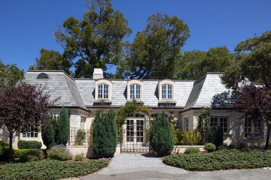 Bathed in sunlight on a quiet, south-facing corner just 3 blocks from the beach in Carmels coveted Golden Rectangle, this French Provincial jewel evokes timeless elegance and European charm. A slate roof, patinaed copper gutters, tall arched French doors and windows, and wrought iron accents grace the limestone and stucco exterior. Inside, vaulted ceilings, hand-hewn wood beams, and Venetian plaster walls elevate the interiors with warmth and sophistication. The grand living room centers around a carved limestone fireplace flowing seamlessly to a refined dining area and a cozy kitchen with its own hearth. The soothing sound of waves drifts through open windows and doors, bringing the coasts rhythm into daily living. A bright, main floor primary suite offers a peaceful sanctuary with direct access to sun-dappled patios, perfect for morning coffee or relaxing after a sunset stroll along the beach. A privately situated 2nd bedroom and bath offer stylish comfort for guests, while an inviting library loft and whimsical childrens bunk bed nook above provide quiet spaces to read or dream. Whether cherished as a romantic pied-à-terre or lived in year-round, this storybook home, complete with garden pathways and a single-car garage, is a rare find in the heart of Carmel-by-the-Sea.