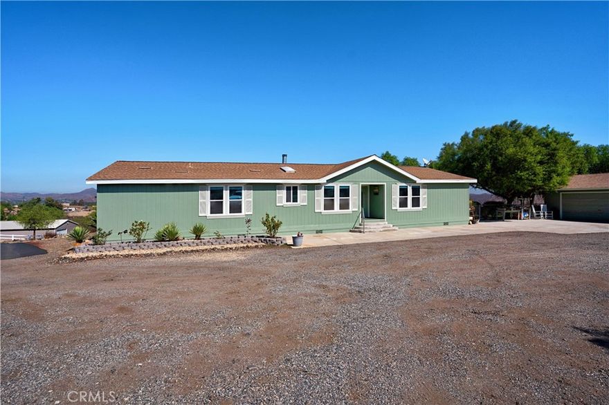 Beautiful hilltop retreat on 4.76 acres with panoramic views! Spacious 4 bed, 2 bath home offers 2,140 sq ft of open living with vaulted ceilings, wood burning fireplace,  and a bright kitchen with island and breakfast nook. Primary suite features huge double head shower,  dual vanities, and walk-in closet. Property includes detached 2-car garage plus 2,000 sq ft pull-through shop with dual 12-ft roll-up doors and 100-amp service—ideal for RVs, boats, or business use. Fully fenced, usable land with multiple flat pads. Peaceful rural setting near I-15, Hwy 74, and Lake Elsinore. Perfect blend of space, comfort, and functionality!
