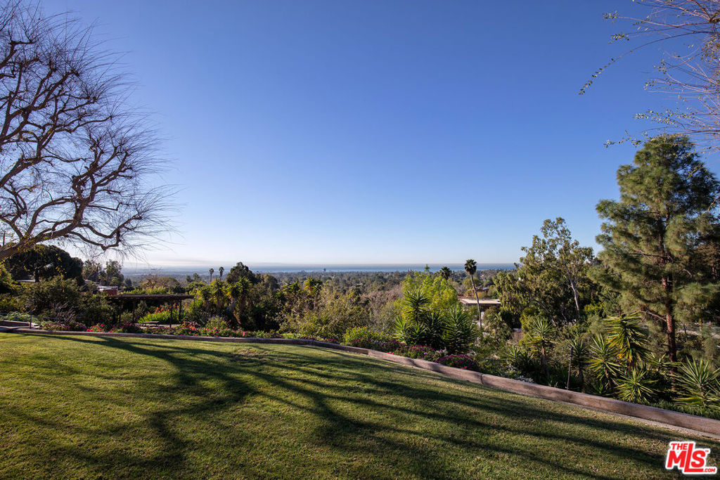 Set on more than an acre of land atop of a covetable ocean-view site in Brentwood, this classic 1949 mid-century modern property presents the opportunity to expand upon the architectural pedigree of the existing residence or to entirely re-envision a new estate. The existing single-story home offers the iconic principles of its mid-century modern design: clean lines, natural materials, and the seamless flow of indoor-outdoor living. The property features 4 bedrooms, 3 bathrooms, an office, and a den, opening into the lush surrounding  grounds. The site itself, which sits among the distinguished estates of Kenter Canyon, offers unobstructed ocean views of the iconic Southern California "Queen's Necklace", the sparkling coastline from the Palos Verdes Peninsula up to Malibu. Per Underbuilt, options of restoration or redevelopment include an addition and remodel totaling approximately 8,988 square feet or a full teardown with the ability to rebuild up to approximately 10,786 square feet. This is the first time the property has been offered on the market with an asking price below $8,000,000. Whether preserved, expanded, or entirely reimagined, this exceptional property blends natural serenity with proximity to Los Angeles' finest dining, shopping, and lifestyle.