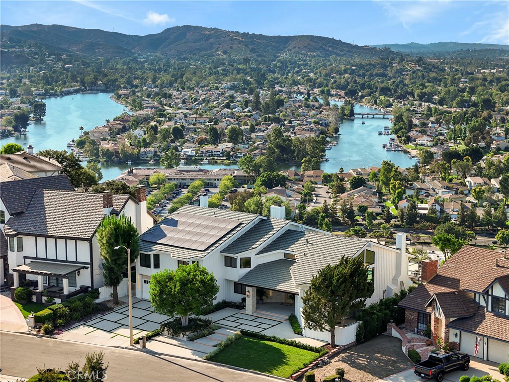 Experience elevated California living in this fully remodeled smart home with sweeping lake views in one of Westlake Village’s most desirable neighborhoods. Seamlessly blending timeless elegance with cutting-edge technology, this residence showcases premium finishes, thoughtful design, and impressive attention to detail throughout. The expansive floor plan offers 4 spacious bedrooms, a dedicated office, bonus room, formal living and dining rooms, and a welcoming family room — ideal for both entertaining and everyday comfort. The custom chef’s kitchen features Taj Mahal marble countertops, high-end appliances, and refined cabinetry, creating a centerpiece worthy of a magazine spread. Sophisticated touches include Italian tile in the bathrooms, LED accent lighting in the bathrooms and staircases, custom interior doors, and three fireplaces for added warmth and ambiance. A sleek wet bar adds effortless functionality for hosting guests. The home is equipped with dual A/C units for zoned climate control and long-term comfort. The luxurious primary suite features a spa-inspired bathroom and a private balcony with serene lake views — a perfect retreat for sunrise coffee or sunset wine. Step outside to a showstopping backyard designed for modern outdoor living. Enjoy a resort-style pool and spa featuring a baja shelf, crisp architectural hardscape, a vertical green wall, and a raised deck with panoramic views stretching across the lake and surrounding mountains. Mature fruit trees line the property, and the home is powered by fully paid-off solar panels, offering beauty, privacy, and efficiency. This turn-key home is a rare opportunity to own a fully upgraded lakeview estate in a premier Westlake Village setting — where luxury, location, and lifestyle come together effortlessly. Virtual tour available: https://my.matterport.com/show/?m=DkFxUHrCYp9