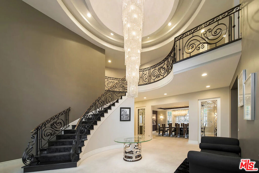 Perched behind private gates in the prestigious Mulholland Estates, this five-bedroom, eight-bathroom estate blends modern luxury with timeless elegance. Soaring cathedral ceilings and a Swarovski chandelier welcomes you into the grand foyer. The open-concept floor plan features a formal living room with fireplace, a family room with built-in bar, a dining room, and a chef's kitchen with top-of-the-line appliances and breakfast nook. The luxurious primary suite is a private retreat with a spacious balcony, fireplace lounge, dual walk-in closets, two spa-like bathrooms, and its own private dry and wet saunas for ultimate relaxation. Outdoors, enjoy a 12-foot deep pool and spa, jacuzzi, outdoor kitchen with BBQ and pizza oven, lush gardens, and multiple observation decks designed for entertaining. Additional highlights include a professional recording studio, library office, staff quarters, and a three-car garage with ample parking. Residents enjoy Mulholland Estates' exclusive amenities, tennis courts, racquetball courts, fitness studios, and playgrounds - all minutes from Beverly Hills and the Valley, and all LA has to offer.