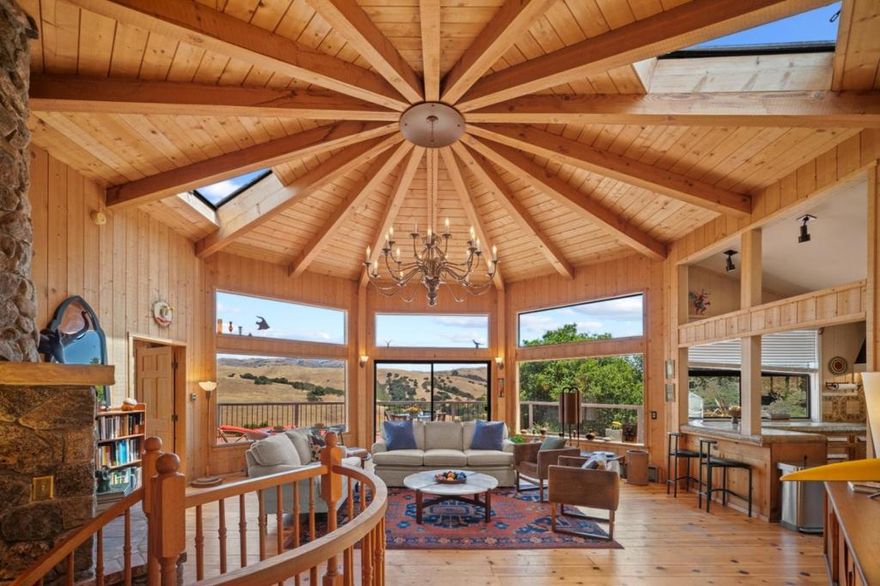 Once Upon a Time in the Golden Hills of Carmel Valley an artist envisioned a sanctuary, a place where inspiration dances in the daylight and serenity deepens under starry skies. Tucked into the tranquil enclave of Los Tulares, just minutes from Carmel Valley Village, this dual residence property delivers on that dream with privacy and panoramic beauty.  Set amid rolling hills and mature oaks, this 3,424 sq. ft. property includes 2 homes, a detached garage, and endless opportunities for flexible living, creative retreat, or income potential. The main house welcomes you with a cabin-style living room, wood-burning fireplace and lit by a striking chandelier. Walls of windows frame sweeping vistas, and the open concept flows into a kitchen designed for function and charm. The main floor also includes the primary bedroom, 2 full baths, and a bonus room. The downstairs level offers a bedroom with full bath, kitchenette, bonus room, and its own entrance, ideal for guests or extended family. In addition, there is a detached barn-style ADU which is a jewel in itself: fully renovated with 2 bedrooms, a bathroom, and laundry.  It offers rustic, modern appeal in a setting that feels worlds away. Outdoors, the magic continues with pathways, a koi pond, cascading waterfall, and multiple decks.