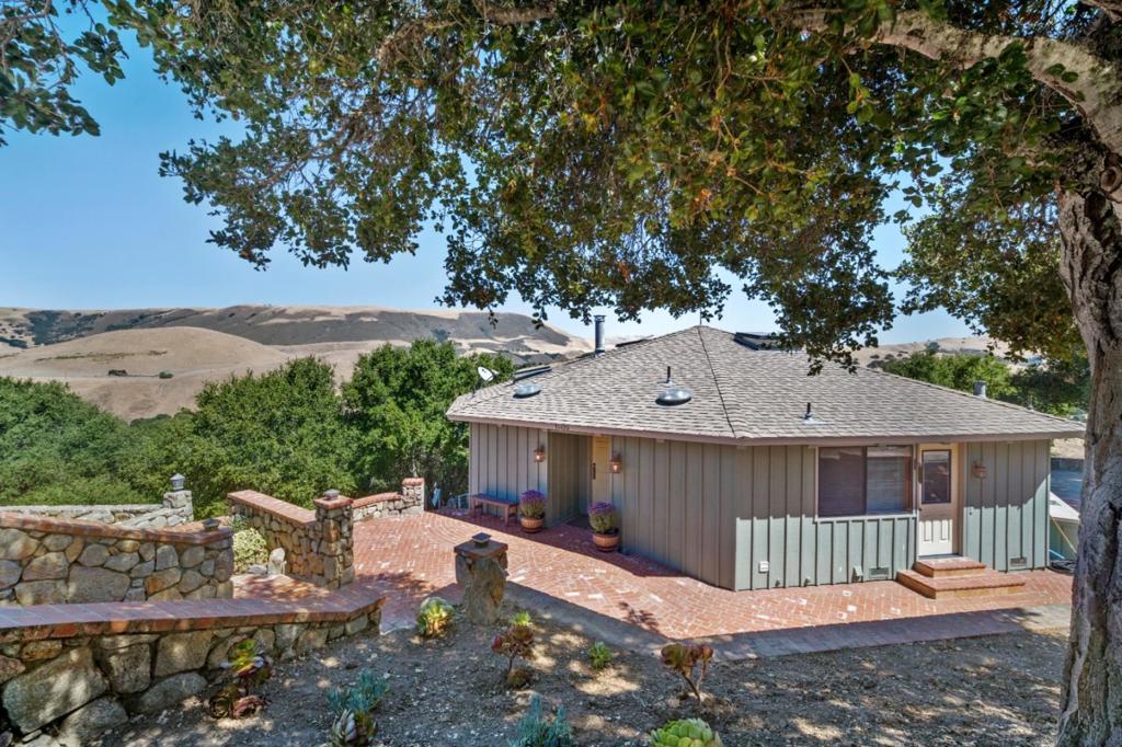 Once Upon a Time in the Golden Hills of Carmel Valley an artist envisioned a sanctuary, a place where inspiration dances in the daylight and serenity deepens under starry skies. Tucked into the tranquil enclave of Los Tulares, just minutes from Carmel Valley Village, this dual residence property delivers on that dream with privacy and panoramic beauty. Set amid rolling hills and mature oaks, this 3,424 sq. ft. property includes 2 homes, a detached garage, and endless opportunities for flexible living, creative retreat, or income potential. The main house welcomes you with a cabin-style living room, wood-burning fireplace and lit by a striking chandelier. Walls of windows frame sweeping vistas, and the open concept flows into a kitchen designed for function and charm. The main floor also includes the primary bedroom, 2 full baths, and a bonus room. The downstairs level offers a bedroom with full bath, kitchenette, bonus room, and its own entrance, ideal for guests or extended family. In addition, there is a detached barn-style ADU which is a jewel in itself: fully renovated with 2 bedrooms, a bathroom, and laundry. It offers rustic, modern appeal in a setting that feels worlds away. Outdoors, the magic continues with pathways, a koi pond, cascading waterfall, and multiple decks.