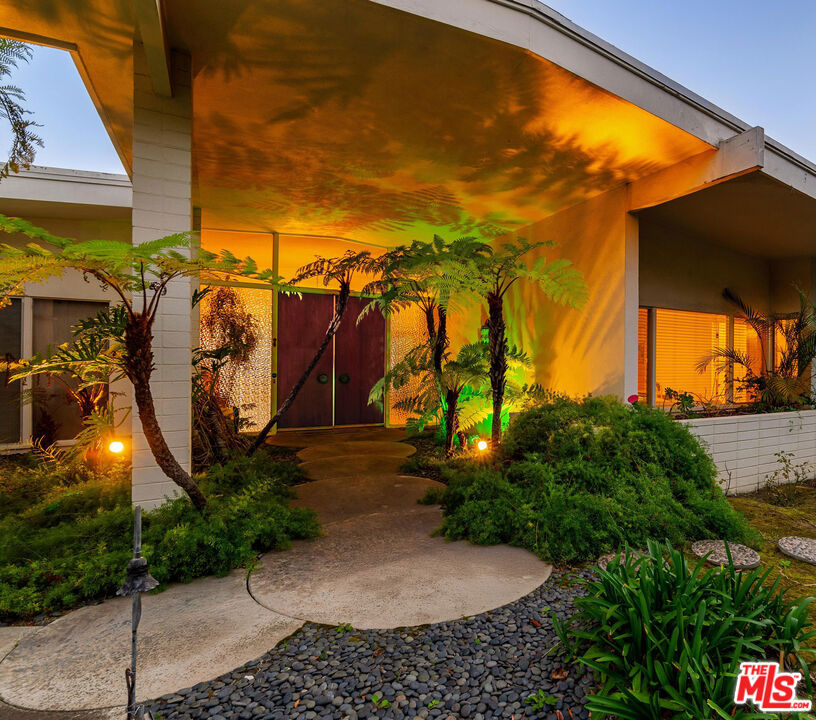 Suave, Stylish & Sophisticated. Hollywood Elite and legendary musicians like Louis Armstrong were entertained here, swayed to the music and were awed by panoramic views from the City to the Ocean. A quintessential Mid Century retreat; a prime location in the Bird Streets. The first time on the market in 60 years, this residence has all the architectural features and open plan living spaces to capture the imagination, to curate this home to sing once again. The front elevation, with gabled entry, secluded courtyard and floating roof car park provide clues to classic modernist interior design featuring of a series of open concept spaces, expertly arranged, all playing directly to the garden, patios, pool and views. A grand formal double door entry unfolds to a massive living room, spacious media room with step down walnut bar, powder room, and large formal dining room - all light-filled spaces and walls of glass, with fluid connections among them. Shift your gaze to the sparkle of City lights beyond. Private quarters include a very large pool-side primary suite with wide open views, multiple closets, dressing room and large bath, plus two generous bedrooms and shared bath. Another wing contains the eat-in kitchen with yet more expansive views, service area and 4th bedroom + bath, all easily updated or reconfigured into a sprawling entertaining kitchen/family room/office wing all its own. Generous use of terrazzo, vintage pristine walnut paneling, and a variety of flourishes uniquely suited to preserving and coveting. Enormous opportunity to add square footage and/or rework the property to create a massive dream home with a generous flat pad, in a location offering homes in excess of $30MM. Don't miss this splendid toe-hold in Doheny Estates.