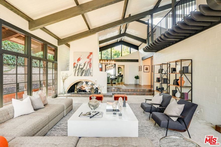 Beyond a walled and gated entrance and up a long drive find this private Mid-Century tennis court estate nestled on a 30,000+ square foot flat lot in prestigious Brentwood Park, north of Sunset. Custom built in 1969 with dramatic block and glass construction, this distinctive residence offers 6,151 SF of living space with 6 bedrooms and 5.5 bathrooms. Featuring soaring two-story ceilings and a two-sided fireplace in the voluminous formal living and dining rooms, lovely formal entry looking into a tranquil courtyard with fountain, large office with corner fireplace and charming spiral staircase to built-in library, swank retro bar, spacious lounge, eat-in kitchen and so much more. While most of the home is on one level, ascend the floating wood staircase to the expansive primary bedroom suite, which includes a grand loft-like sitting room looking over the living room for a luxurious and comfortable retreat. The architecturally interesting design, wrapping around a central courtyard, creates a sense of openness and connection between different areas of the home while maintaining distinct spaces for privacy and relaxation. The attached pool house/guest house includes a sauna, perfect for unwinding after a swim or game of tennis on the North/South lighted tennis court with viewing pavilion. The four-car garage includes EV charging capacity and built-in storage plus a workshop. For sale for the first time in almost 40 years, this home stands ready for your transformational touch and is ready for a new generation to create their own memories. Trust sale.
