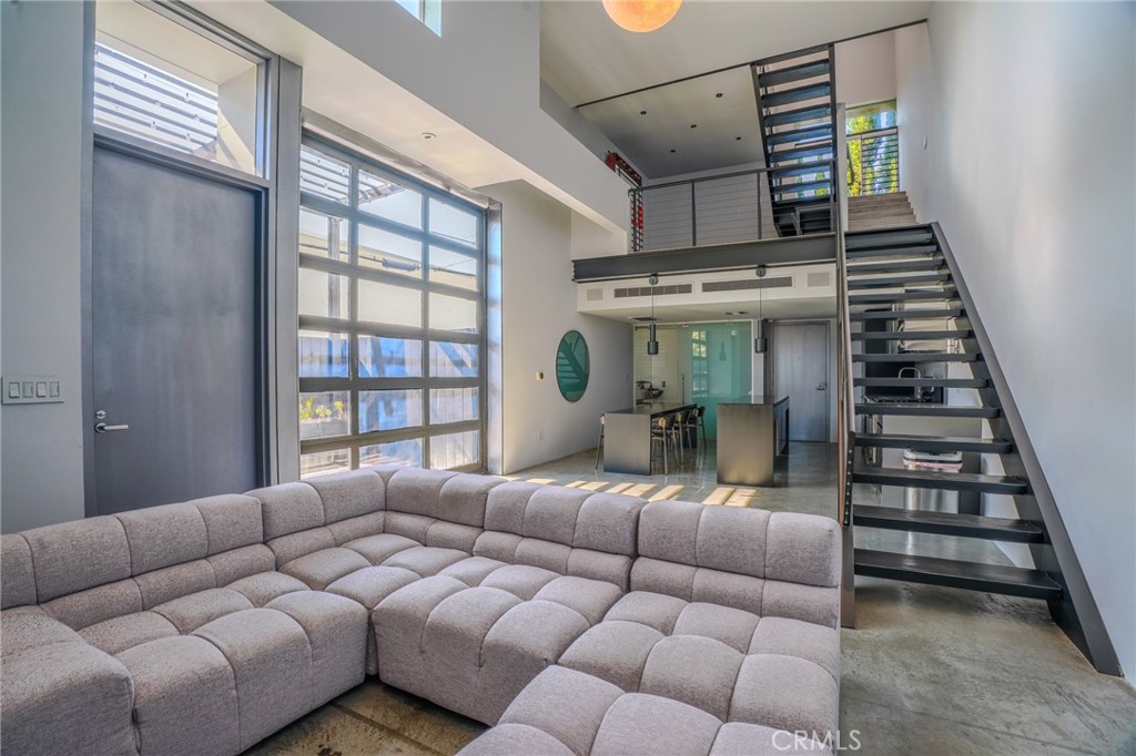 West Hollywood living at its finest! Located in a highly sought after AIA Award-Winning Building, designed by prolific Architects Pugh-Scarpa! This modern architectural gem has been intricately designed to captivate the senses of any contemporary design enthusiast. Soaring 17-foot ceilings create an expansive, light-filled living space with effortless indoor-outdoor flow. The living space has polished concrete floors, large pocket windows, and a sliding metal-and-glass wall which opens to an oversized patio— complete with planter boxes, pergola, and high privacy fencing that is a perfect place for entertaining and relaxing. On the second level is a mezzanine-style office/flex space overlooks the living room, offering a dynamic and inspiring workspace. The top-floor primary suite features floor-to-ceiling windows with sweeping views of the Hollywood Hills. A flexible second room at the top level could potentially be used as a guest room, den, or studio. The spa-like primary bathroom includes a glass-tiled walk-in shower and tranquil ambiance. Other great features of the home include a Sub-Zero refrigerator, Dual Zone AC, and Ample storage throughout. Also includes gated subterranean parking and an HOA common area animal space/run at the back of the lot. All just moments from iconic Hollywood and L.A. landmarks—perfect for urban dwellers and design lovers alike.