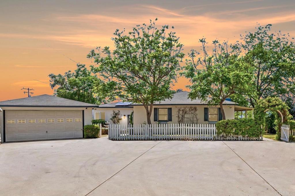 Welcome to 3261 Mary Lane, a residence that perfectly blends timeless character, modern comfort, and income potential, all set on a usable half-acre lot with sweeping 300-degree panoramic views of sunrises, sunsets, and rolling hills. The main house spans 1,933 sq. ft. with 4 bedrooms and 2 bathrooms, thoughtfully updated with new paint, flooring, and stylish finishes, featuring a bright, open layout filled with natural light and a wraparound porch that captures the views like living artwork. The large kitchen boasts updated cabinetry and counter space, flowing seamlessly into the dining and living areas, where a striking fireplace anchors the entertaining space, creating the perfect gathering spot for family and friends with panoramic views from every window. The primary suite offers a tranquil retreat with bay windows framing picturesque views, an ensuite bathroom with elegant finishes including a standalone tub, large shower, double sink, and a walk-in closet with generous storage. Adding to the versatility of the property is a detached guest studio, complete with its own kitchen and bath, perfect for multigenerational living, extended guests, or as a rental providing both flexibility and income opportunity. Outdoors, the expansive half-acre lot is a true lifestyle setting, with mature landscaping offering privacy and plenty of room for gardens, play, or future expansion. The backyard has served as a romantic wedding venue and hosted many parties beneath Escondido’s golden skies, while the gated driveway (automated gate) accommodates up to 8 cars and has even doubled as a pickleball court, highlighting the property’s adaptability to your needs. Modern comforts include fully owned solar panels for energy savings, a high-end whole-house fan for year-round comfort, and an EV charger hookup, making the home as practical as it is beautiful. With its white picket fence, cottage design, and unmatched curb appeal, this property embodies North County charm at its finest. Convenience is unmatched, with top-rated schools, Kit Carson Park, Vineyard Golf Course, and Westfield North County Mall all within 1 mile, just 5 miles from the San Diego Safari Park, and 20 minutes from the coast, offering an ideal balance of privacy, charm, and accessibility. Whether you’re seeking a peaceful retreat, a family-friendly home, or an investment with rental income, 3261 Mary Lane delivers it all. With its views, versatile ADU, spacious lot, and rare combination of history and lifestyle, this property is truly one-of-a-kind. Don’t miss your chance to own a slice of North County charm - schedule your private showing today. (2 car garage currently converted to ADU can easily revert back to 2 car garage)
