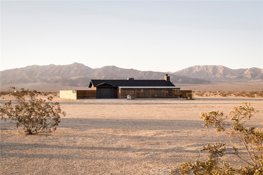 Escape to modern comfort in this beautifully designed 2-bedroom, 2-bathroom home in the heart of Wonder Valley, just 20 minutes from the eastern entrance of Joshua Tree National Park and downtown Twentynine Palms. This fully furnished property is an active and successful short-term rental, thoughtfully curated with mid-century modern touches, earth tones, and spa-like bathrooms that create a warm, organic ambiance.
Inside, concrete floors anchor the space in natural texture, while the open layout enhances flow and functionality. The show-stopping wooden slat front porch is both sculptural and functional, featuring engineered sliding doors that offer privacy when desired and open to extend the living space outdoors. The kitchen and living areas are bathed in natural light, and both bathrooms feature modern finishes and serene design.
What truly sets this home apart is the integration of underground utilities at the main house, allowing uninterrupted desert views and reinforcing the seamless blend of architecture with nature. The property also includes an attached garage approximately 272 square feet in size, a 754 square foot barn with electrical already in place, and an original 200 square foot homestead cabin—offering a combined 1,226 square feet of additional space with endless potential for creative expansion, guest accommodations, or studio use.
The backyard is fully fenced with a beautifully crafted wooden privacy wall and offers sweeping 360-degree mountain views. Outdoor amenities include a swing bed, shaded dining area, fire pit lounge, and a private outdoor shower—perfect for soaking in the stillness of the desert sky. With no water bill thanks to a private well and a setting in one of the High Desert’s most eclectic and artistic communities, this property blends rural tranquility with modern ease.Located just minutes from the iconic Palms bar and surrounded by wide-open desert beauty, this is your chance to own a rare gem in one of the High Desert’s most eclectic and inspiring communities. Whether you're looking to invest, escape, or create, this property delivers the perfect balance of privacy, design, and potential.