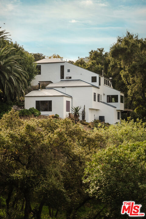Situated behind gates and commanding views of the rolling canyons and hills of Topanga, this mountain masterpiece is perfectly placed within 2.5 acres of established gardens. Nothing says welcome home better than the reveal of this stunning home as the gate opens. Originally built in 1980 and just recently updated this contemporary estate rises up from the idyllic canyon setting to form a tranquil juxtaposition. Effortless in its easy flow for entertaining and indoor/outdoor living with its open airy layout, it is also warm and gentle on the soul with the use of the finest of materials and modern conveniences. Designed by Canadian architect W. Earl Wear and remodeled with reverence and sensitivity to its natural environment, this luxurious hillside retreat encompasses all that canyon living has to offer. The open-plan design also features a large attached studio with high ceilings. While you may feel utterly removed from the everyday bustle, you are only minutes to the sunny beaches of Malibu and the laidback town center of Topanga Canyon.