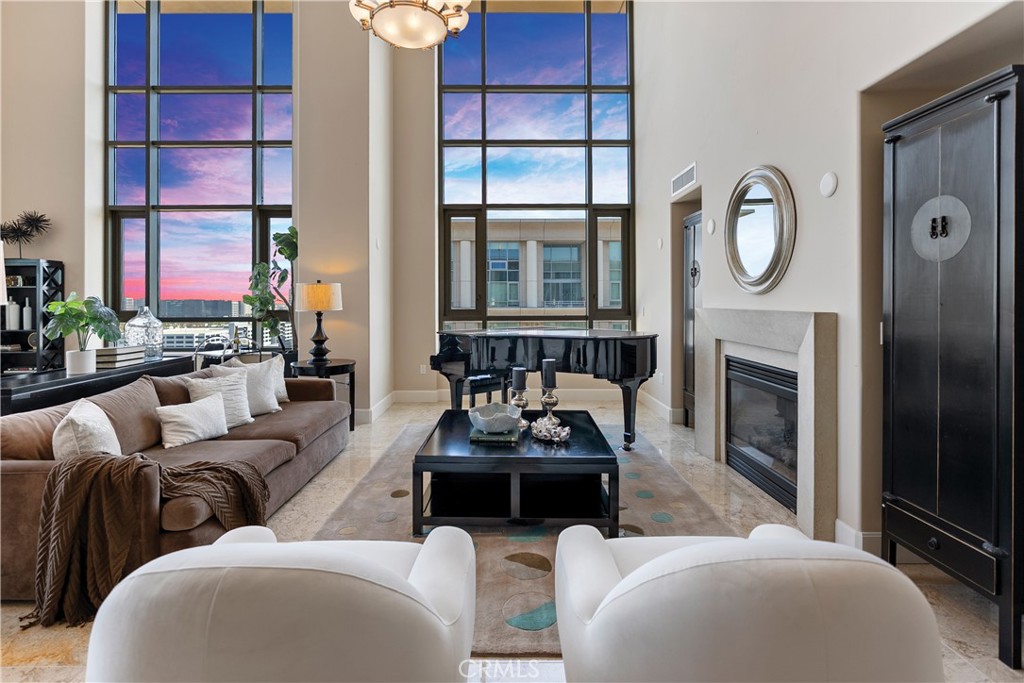 Experience luxurious penthouse living in the heart of Irvine — an extraordinary, 2-story elegant and sophisticated residence. This home is a masterpiece and virtually unmatched anywhere in OC. You are immediately captivated by the breathtaking 2-story windows flooding the open-concept Great Room with natural light and sweeping panoramic views. A magnificent staircase ascends to the second level where you’ll find the opulent primary suite and an elegant guest bedroom. This exquisite penthouse is a rarity, as very few buildings in the prestigious areas of South OC offer such exceptional 2-story Penthouses. It’s like living in Manhattan, but with the added luxury of being just 10 to15 minutes from fabulous beaches! The Great Room is open and inviting, with a formal dining area integrated to capture the panoramic views. The kitchen is extraordinary, featuring a large island and upgraded Italian cabinetry. A spacious walk-in pantry and a generous laundry room complete this haven. The main level also offers a luxurious bedroom with large en-suite bathroom and magnificent views. There’s an intimate Library which can also serve as an office. Showcase your wine collection in a charming walk-in Wine Room. The primary suite is an oasis of tranquility, featuring a fireplace and a seating area perfect for relaxing. Enjoy the massive view from all angles! The adjoining bathroom is equally lavish with custom cabinetry, elegant freestanding tub, walk-in shower, and massive walk-in closet that feels like a private dressing room. The other guest suite is spacious. For outdoor living, there’s the large, private balcony area, perfect for al fresco dining while enjoying the expansive views. The community itself is a resort within a resort, offering a wide array of amenities. Join a cycling class, enjoy the charming tea and coffee shop, a retail shop, and casual dining. The expansive association pool and deck, meeting rooms, and bbq areas are perfect for relaxing or socializing with friends and neighbors. The gym is enormous, and includes a steam room. Enjoy playing billiards or spending time in the Social Club. Homeowners enjoy a private building concierge available to assist with any need. Enjoy three parking spaces in the garage on the main level, plus your own storage unit! This penthouse is truly a dream come true — an opportunity to own one of the finest residences available in the most coveted location. It is a rare treasure that must be seen to be fully appreciated.