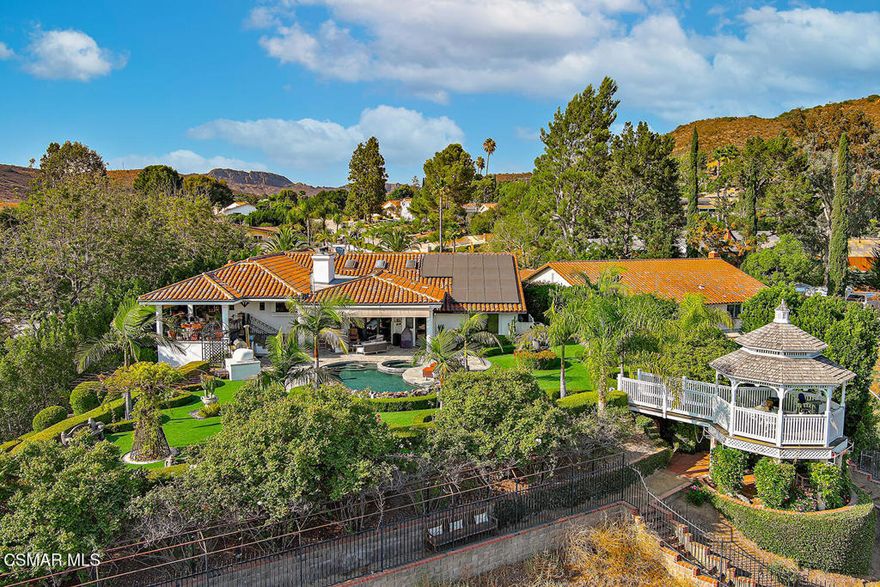 Located in the charming Thousand Oaks community of Lynn Ranch ~ you will find this stunning  Santa Barbara Spanish Revival style home with a backyard, view and location that is unrivaled in all of the community! THE SOLAR SYSTEM IS OWNED BY SELLER! THERE IS NO LEASE, IT WILL STAY WITH THE PROPERTY! AND-- THERE ARE 4 BATTERIES IN THIS SYSTEM! Set back off the street with a dual gated circular driveway-the curb appeal is fabulous. There is  enough parking for approx.  5 + cars. This home offers 4 bedrooms, 3 baths, gourmet kitchen, wine cellar and over 3800 sq. feet of living space.   As you enter through the massive iron doors you realize very quickly this property is like no other.  Inside you are greeted by the  grandest of living rooms with a 2 story vaulted ceiling, spectacular wood beam finishes, rich warm colored hardwood floors and carpets throughout and a fireplace designed for a sweet story straight out of an English Castle.  The kitchen offers Sub Zero appliances 2 ovens, an island and a wonderful eating area, which opens out to the upper terrace patio with views. There is the most charming wine cellar that can hold up to 1500 bottles of wine, a huge laundry room. and a fireplace trimmed in stacked stone .   The rustic elegance brings such character and charm to this home.  There are 3 spacious bedrooms and 2 bathrooms beautifully remodeled. There is a lovely primary suite with an attached remodeled bathroom, walk in shower and soaking tub.   ~ If you wish to have a cold glass of wine and enjoy those sunsets, step out of the kitchen onto the upper terrace!  There are automatic shades, ceiling fan and endless views. This is the perfect location to be above the grounds and have a fabulous dinner party al fresco!  The lower patio offers a  stainless steel BBQ  and the  absolute show stopper of all is a PIZZA OVEN all the way from Italy!! This portion of the yard is the epitome of perfection for entertaining~~And beautiful furnishings (which stay)  to enjoy with your guests alongside the pool.The saltwater pool and spa are perfectly situated  for swimming and enjoying the grounds. Turf has been added here in the rear yard.  This property was on the Westlake Village Gardens Tour for many years ~ so you can understand how thoughtfully  it is all laid out, how beautiful the trees, roses,  iron artwork and mosaics are!  After you enjoy the built ins, take a walk down the sweet brick path that ends at a magical garden and greenhouse. Then continue on the path and just when you think you have seen everything this property has to offer--- look around at the magnificent canyon and mountains. This property looks out to the Arroyo Conejo Natural Reserve with canyons, hills and a running stream below. The vistas are magnificent! The sunsets are so beautiful, you will feel they were hand painted just for you! This property is full of charm with joyful little areas, benches to sit and meditate, views, gazebo, roses, pathways and so much more. It is magical, It is mystical and It's calming.~~  You will truly  fall in love with this property and this stunning estate.