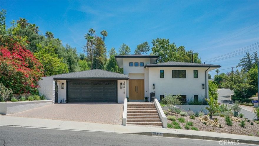 Sophisticated newly remodeled and expanded residence tucked into the hills of Woodland Hills. Positioned on a prime corner lot, this 5-bedroom, 5-bath home seamlessly blends clean modern design with a touch of coastal-inspired style. The attached addition and carefully selected upgrades elevate both function and beauty. Wide-plank white oak floors, all-new interior doors, a brand-new roof, new HVAC, and energy-efficient windows create a light-filled and elegant environment throughout.



A dramatic 16-foot foyer entry sets the tone, leading into the open-concept living area centered around a sleek stone fireplace. Expansive windows and sliding glass doors flood the interiors with natural light while creating a seamless connection to the outdoors. The adjacent formal dining room—with its own oversized glass doors—opens directly to the landscaped backyard, perfect for entertaining or enjoying an indoor-outdoor lifestyle.



The chef’s kitchen is a statement of both style and practicality, offering abundant custom cabinetry, generous counter space, a large island with seating for six, a five-burner cooktop, and double ovens. A sliding door from the kitchen opens to a built-in BBQ, ideal for al fresco dining.



The primary suite serves as a luxurious private escape with dual walk-in closets and a spa-inspired bath featuring double vanities, a soaking tub, walk-in shower, and private water closet. Two additional guest suites each include their own full bathrooms with tile and granite finishes for comfort and privacy. On the lower level, two spacious bedrooms share a beautifully updated bath with double sinks, a tub/shower combo, and elegant finishes.



A large laundry room is equipped with custom cabinetry, shelving, folding counter, and utility sink, plus two extra storage closets. The backyard is designed for both leisure and play, featuring a spacious patio, basketball court, and grassy area.



Set in a highly desirable neighborhood with access to award-winning schools—Calabash Charter Academy, Hale Charter Academy, and El Camino Real Charter High School—this property offers the complete package: refined design, generous space, and a prime location. A rare turnkey opportunity in one of Woodland Hills’ most sought-after communities.