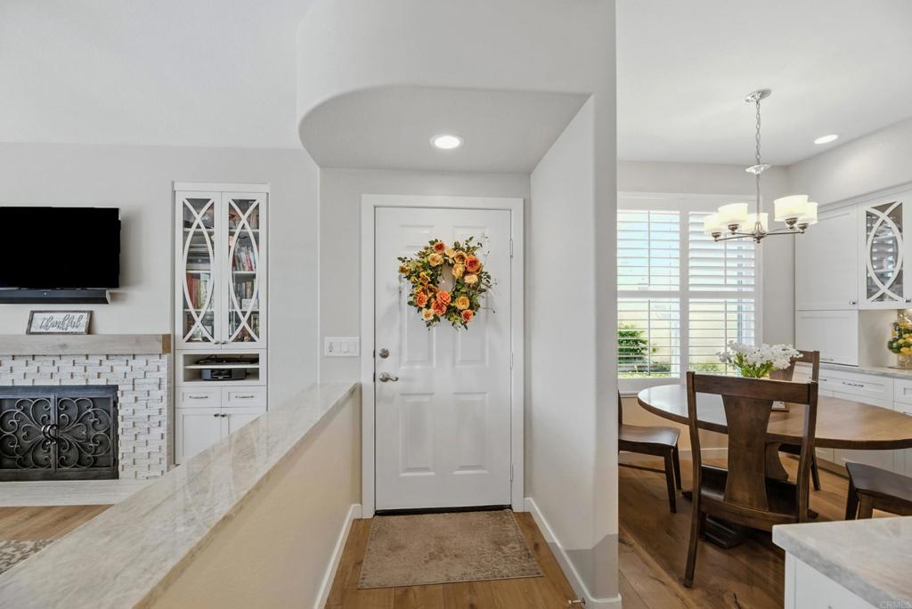 DISCOVER THE BEAUTY BEHIND THE GATES OF VISTA DEL LAGO! Highly upgraded townhome with panoramic mountain and sunset views. Upon arriving you will notice the extra space between this building and the neighbor providing privacy and a larger than most backyard updated with stamped concrete, roses, fruit trees, an aluminum patio cover and newer vinyl fencing. Design winning floorplan when built by DR Horton for its spacious/open design. Remodeled kitchen has all newer cabinetry and plenty of soft close drawers and soft close doors with polished nickel hardware topped with gleaming quartzite countertops and shiny subway tile, stainless steel Whirlpool 5 burner gas stove, oven, French door refrigerator, Bosch dishwasher, large farm sink with polished nickel faucet and informal dining area, polished nickel light fixture and updated canned lighting opening to a large great room with engineered wood flooring throughout featuring a gas fireplace with custom screen doors, stone jigsaw piece effect facing enhanced by a wood mantle matching the floors. Entire home has newer, dual paned windows solid wood interior doors and plantation shutters. Upstairs are dual primary suites-one with a panoramic view has an amazing updated tile walk in shower and raised dual vanity with quartz countertops, newer cabinetry and polished nickel hardware, a custom fan outside the shower and walk in closet. Linen cabinets are in the hall between this and other bedroom suite with its own full bath and large closet. The two car garage opens into the laundry room with side-by-side washer/dryer and custom cabinetry above. Located in the highly acclaimed Poway Unified School district this multi million dollar recreation center facility features 2 pools (one a heated lap), 2 spas, exercise room, 4 lighted tennis/pickleball courts, banquet room and more! LOW HOA and NO MELLO ROOS.
