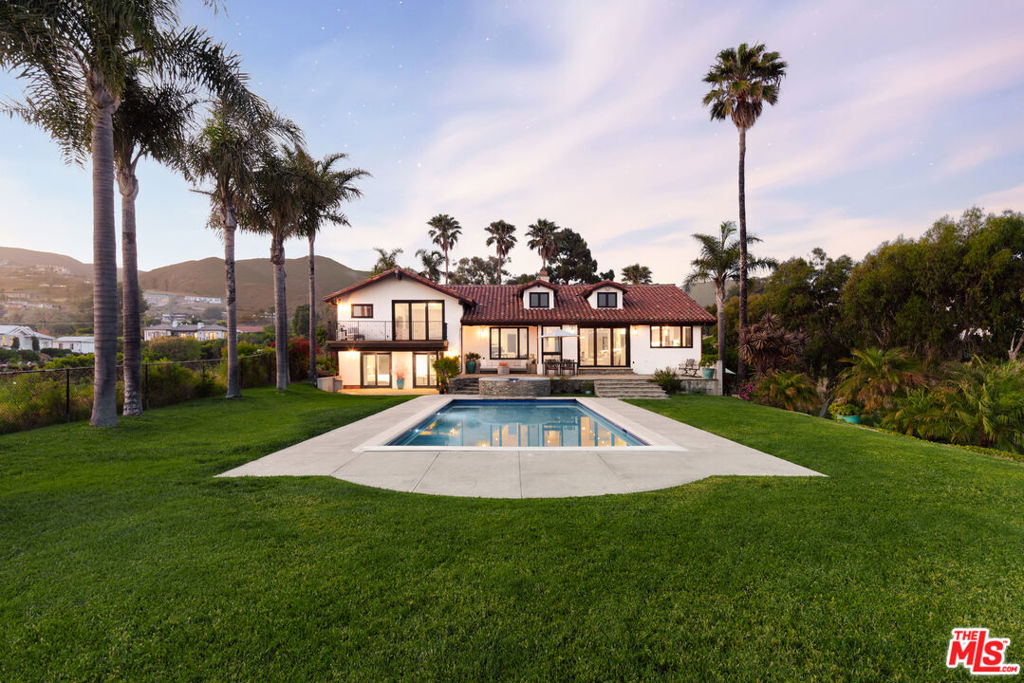 Set atop a private, elevated rolling knoll in prestigious Malibu Park, this reimagined and romantic Modern Mediterranean estate offers elevated coastal living on over two park-like acres of fully usable land with unobstructed ocean views and exceptional privacy. This is a rare opportunity to own a legacy estate that defines luxury coastal living in Malibu. A long, tree-lined driveway leads to a beautifully renovated 4,898 sq ft main residence, showcasing wide-plank white oak floors, custom cabinetry, and a sunlit open-concept layout. The designer kitchen features quartz countertops, brand new appliances and sweeping views of the Pacific. Indoor living spaces flow effortlessly to a covered heated terrace, sparkling saltwater pool, and manicured lawn. The home offers 5 bedrooms and 6 bathrooms across three structures, including a 1,100 sq ft guest house with expansive ocean views, a sun-lit deck off the main bedroom, vaulted ceilings, two brick fireplaces, full chefs kitchen, and a lower level featuring a large bonus room and full bath ideal for extended stays or a private office. A separate 500 sq ft studio offers additional flexible space for a theatre, creative work or wellness. Outdoors, California native landscaping surrounds the property, with sycamore, oak, fruit trees, coastal sage, adding natural beauty and privacy. A vine-draped pergola, tiered fountain, and ocean-facing lounge areas create the ultimate setting for entertaining and relaxation. Additional upgrades include a full-house generator and whole-house water filtration system. Located minutes from Zuma Beach, Malibu schools, and scenic trails, this one-of-a-kind estate is the perfect blend of luxury, nature, and modern California living.