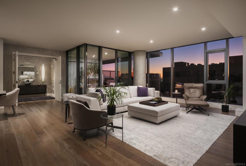 In the heart of one of San Diego’s most prestigious neighborhoods, this designer residence at The Park Bankers Hill embodies the pinnacle of contemporary luxury, with interiors curated to perfection and an atmosphere of timeless sophistication. Upon arrival through your dedicated direct-access elevator, this 1,875-square-foot home reveals a world of meticulous craftsmanship and design. Floor-to-ceiling glass walls flood the interiors with natural light and frame the surrounding cityscape, while two private terraces totaling more than 320 square feet create an effortless connection to the outdoors. Every element of the residence has been thoughtfully elevated by Esteban Interiors, one of San Diego’s most celebrated luxury design firms, whose vision infuses the home with understated glamour. Venetian plaster walls, Phillip Jeffries designer wallpaper, and sculptural selenite sconces set a refined tone, while a statement Bocci 18 chandelier crowns the dining space with luminous artistry. Lutron electric shades and custom built-ins complement the interiors, blending beauty and function in equal measure. At the heart of the home, the chef’s kitchen is both dramatic and functional, showcasing Italian Boffi cabinetry, a striking Caesarstone waterfall-edge island, and top-tier Miele appliances. The open-concept living and dining spaces unfold across DuChâteau hardwood floors, soaring ceilings, and seamless transitions to a private terrace adorned with a Valakas marble encased fireplace, designed to transform the surrounding views into living art. The primary suite is a sanctuary of serenity, featuring a custom California Closets wardrobe and expansive closet, spa-inspired marble slab-encased ensuite with dual vanities, and blackout electric shades that ensure restful tranquility. The secondary bedroom mirrors the same elevated finishes, perfectly suited for guests or a private office. As a resident of The Park, you’ll enjoy an unparalleled suite of world-class amenities: a resort-style pool and spa, expansive fitness center and yoga studio, club room, wine room, dog wash room, billiards and poker lounge, and a private outdoor owner’s terrace with fire pits and BBQs. Homeowners are granted exclusive access to two fully furnished guest suites five nights a month, completely included for a nominal $275 cleaning fee. Additional upgrades include two side-by-side parking spaces with EV charging and a large storage unit. Perfectly situated in the heart of historic Bankers Hill, this residence places you moments from Downtown’s vibrant energy and San Diego’s finest dining, while Balboa Park’s world-class museums, botanical gardens, and scenic trails lie just steps away. More than a home, this residence offers a rare opportunity to experience a lifestyle where luxury, design, and location converge in perfect harmony.