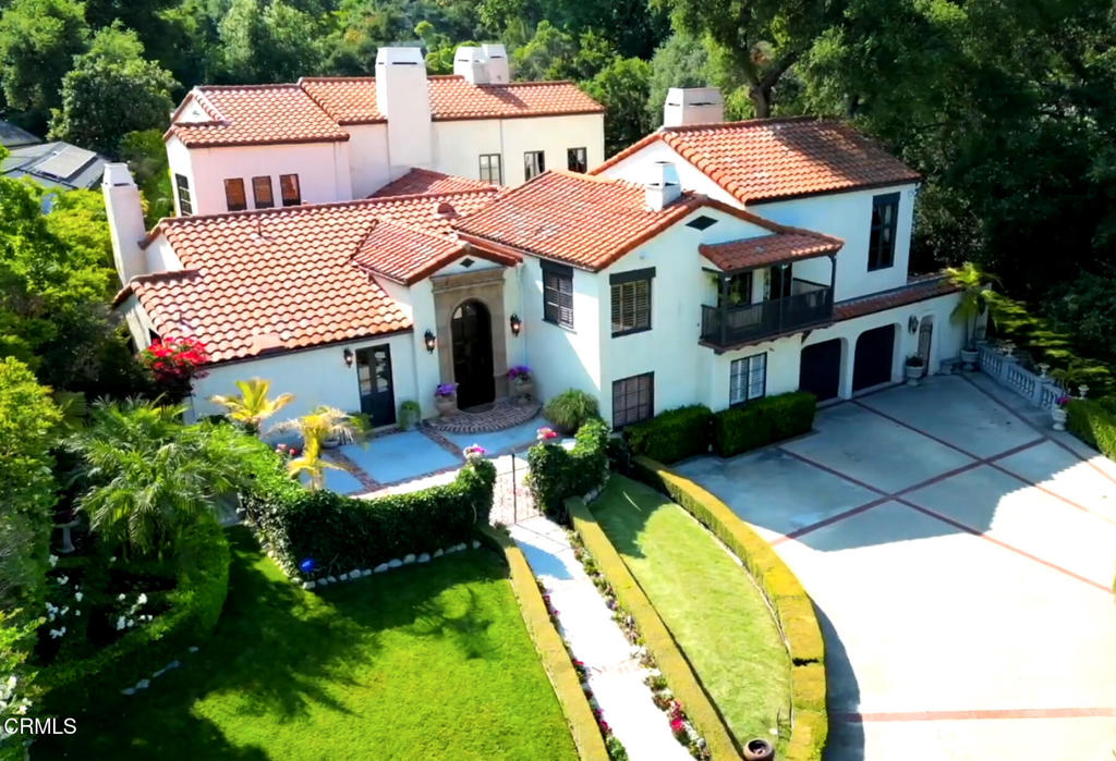 Welcome to the enchanting Orrin White House--an extraordinary 1924 estate originally designed by celebrated architect Garrett Van Pelt, Jr., for acclaimed Plein-Air painter Orrin White and his family. One of the first homes in the area, this rare architectural gem was thoughtfully sited for its breathtaking views of Mt. Wilson and the San Gabriel Mountains, which inspired White's artistry. The frontage is unusually generous at 160 feet. Tucked behind tall hedges and a gated entrance on over half an acre of lush, private grounds, this home is a sanctuary of peace and refinement. The current owners, only the second caretakers of the property in its century-long history, have masterfully restored and updated the residence with a reverence for its original character. Enter the grand formal entry past the 9-foot custom alder front door where 12-foot ceilings, handcrafted plaster cornices, and a Swarovski bronze and crystal chandelier set a tone of quiet elegance. The formal living room is breathtaking--anchored by 18-foot-fitted-old-growth redwood beams, a 2-story window framing majestic oaks, a wood-burning fireplace, and original stamped-concrete floors, with a choir loft above. The gracious formal dining room accommodates 14 guests. It exudes romance with a fireplace, custom wrought iron pocket gates, and French doors that open to the gardens. The chef's kitchen, outfitted with vaulted, beamed ceilings, French doors to a front courtyard and side patio, and top-tier appliances including a Viking 6-burner stove and Sub-Zero refrigerator. A built-in bar with hammered copper sink and beverage fridge completes the space. Up a half-flight of stairs lies an entertaining level with a family room and an impressive game room featuring a vaulted ceiling, wet bar, and French doors opening to an exterior stairway. With 5 bedrooms and 5.5 bathrooms, this home offers generous space. The luxurious primary suite is a true retreat, with 16-foot ceilings, dual fireplaces, and a sitting room. Modern upgrades include updated electrical and plumbing systems, foundation bolting, 3-zone HVAC, a music system, and partial dual-pane windows. Outside, the grounds evoke a European resort experience. Relax beneath a canopy of heritage oak trees, take a dip in the sparkling pool or spa, enjoy the built-in BBQ, or gather around the large outdoor fireplace. There are 7 fireplaces throughout. A rare fusion of historic artistry and modern luxury, this is more than a home--it's a living legacy.
