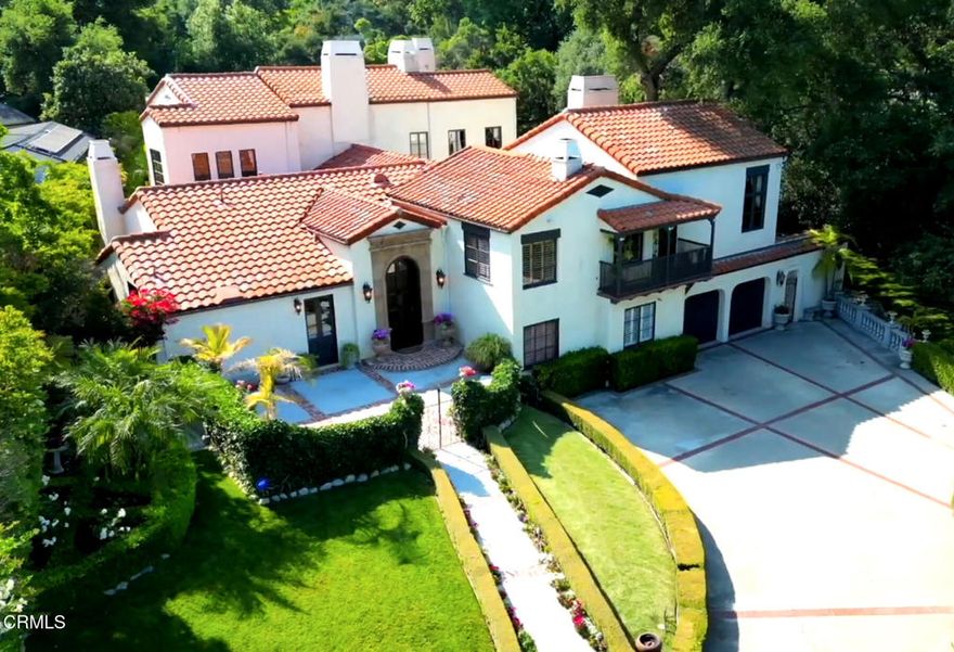 Welcome to the enchanting Orrin White House--an extraordinary 1924 estate originally designed by celebrated architect Garrett Van Pelt, Jr., for acclaimed Plein-Air painter Orrin White and his family. One of the first homes in the area, this rare architectural gem was thoughtfully sited for its breathtaking views of Mt. Wilson and the San Gabriel Mountains, which inspired White's artistry. The frontage is unusually generous at 160 feet. Tucked behind tall hedges and a gated entrance on over half an acre of lush, private grounds, this home is a sanctuary of peace and refinement. The current owners, only the second caretakers of the property in its century-long history, have masterfully restored and updated the residence with a reverence for its original character. Enter the grand formal entry past the 9-foot custom alder front door where 12-foot ceilings, handcrafted plaster cornices, and a Swarovski bronze and crystal chandelier set a tone of quiet elegance. The formal living room is breathtaking--anchored by 18-foot-fitted-old-growth redwood beams, a 2-story window framing majestic oaks, a wood-burning fireplace, and original stamped-concrete floors, with a choir loft above. The gracious formal dining room accommodates 14 guests. It exudes romance with a fireplace, custom wrought iron pocket gates, and French doors that open to the gardens. The chef's kitchen, outfitted with vaulted, beamed ceilings, French doors to a front courtyard and side patio, and top-tier appliances including a Viking 6-burner stove and Sub-Zero refrigerator. A built-in bar with hammered copper sink and beverage fridge completes the space. Up a half-flight of stairs lies an entertaining level with a family room and an impressive game room featuring a vaulted ceiling, wet bar, and French doors opening to an exterior stairway. With 5 bedrooms and 5.5 bathrooms, this home offers generous space. The luxurious primary suite is a true retreat, with 16-foot ceilings, dual fireplaces, and a sitting room. Modern upgrades include updated electrical and plumbing systems, foundation bolting, 3-zone HVAC, a music system, and partial dual-pane windows. Outside, the grounds evoke a European resort experience. Relax beneath a canopy of heritage oak trees, take a dip in the sparkling pool or spa, enjoy the built-in BBQ, or gather around the large outdoor fireplace. There are 7 fireplaces throughout. A rare fusion of historic artistry and modern luxury, this is more than a home--it's a living legacy.