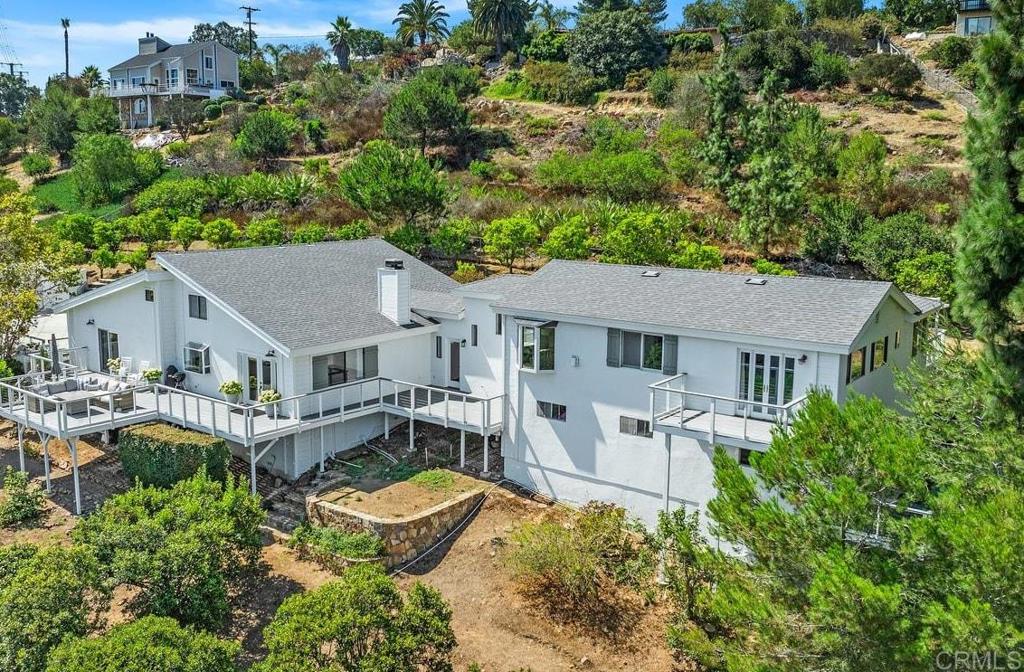 Welcome to this spectacular property that seamlessly blends spacious living, natural beauty, and versatility. Nestled on a generous 1.29 acres in a private neighborhood, this stunning home spans 3,075 square feet and features 3 bedrooms and 2.5 bathrooms. The recently renovated studio apartment, complete with a kitchenette and bathroom, is ideal for multi-generational living or rental potential. The main home greets you with a grand entrance that flows into an inviting open-concept layout adorned with tall beamed ceilings. The expansive living, dining, and kitchen areas are designed for entertaining, featuring large windows that flood the space with natural light and provide breathtaking views that extend onto an oversized deck. The kitchen is a chef’s delight, offering ample space, a walk-in pantry, and views of the picturesque surroundings. Upstairs, a charming loft overlooks the main living area and features a huge closet offering a plethora of storage, making it a perfect space for a home office, hobby area, or guest accommodations. The primary bedroom serves as a tranquil retreat, boasting generous proportions with dedicated office and sitting areas, an oversized cedar-lined closet, an en-suite bathroom, and access to two private decks. The additional bedrooms are also spacious, ensuring comfort for family and guests, complemented by a beautifully designed “Jack and Jill” bathroom featuring modern updates. Step outside to discover your personal oasis. The large patio is surrounded by lush landscaping and mature fruit trees, including kumquats, oranges, lemons, and guavas, providing a delightful harvest throughout the year. This serene outdoor space is ideal for relaxation and taking in the stunning views. Located in the desirable area of San Marcos, this home offers convenient access to shopping centers, award-winning schools, restaurants, parks, and the scenic Lake San Marcos with its renowned golf courses. Plus, enjoy the advantage of no HOA or Mello Roos fees! Don’t miss the chance to make this exquisite property your own.