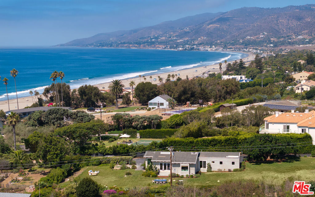Nestled in a prestigiouscommunity in western Malibu with close proximity to the high school,this luxury residence invites you in with its meticulously landscaped and gated yard onapproximately 0.8 acres. Enter into a stunning foyer, where wood-beamed ceilings and rich wood floors set a warm and welcoming tone. Bathed in natural light, the home offers an ideal blend of classic charm and modern convenience.The living room, adorned with wood-beamed ceilings and sleek wood floors, features sliding glass doors that open to the expansive backyard, making it a perfect space for indoor-outdoor living. Just off the living room, the kitchen is a culinary dream, featuring quartzite countertops, a large stone island with a hood fan above a five-burner range, and top-of-the-line Viking and Bosch appliances. The kitchen offers breathtaking ocean and Point Dume views, creating a serene backdrop for cooking and entertaining.The primary suite offers a peaceful retreat with ocean views, a cozy reading nook, and a walk-in closet. Its high, wood-beamed ceilings and bay window enhance the room's airy, tranquil atmosphere.Outside, the sprawling backyard offers lush grass lawns and views of both the ocean and surrounding mountains. With ample parking, this home combines luxury, comfort, and natural beauty in one exquisite package.