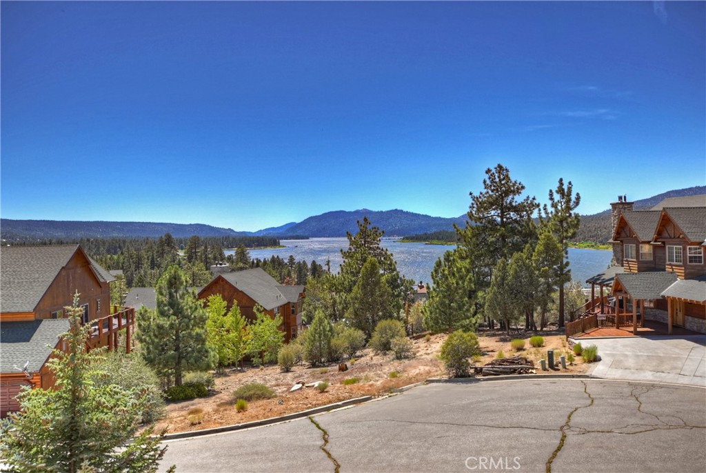 Discover stunning panoramic views of Big Bear Lake and an Eagle Preserve from this beautifully crafted log-sided home located in the highly sought-after Castle Glen Estates. Situated on a cul-de-sac street, this custom mountain retreat features a spacious open-concept great room with vaulted knotty pine tongue-and-groove ceilings and log accents, a dramatic floor-to-ceiling river rock fireplace, and rich wood accents throughout. The gourmet kitchen includes granite slab countertops, stainless steel appliances, knotty pine cabinetry, a large center island, and a built-in coffee maker – perfect for entertaining. With four bedrooms plus a loft, there’s room for the whole family. The main-level primary suite includes a cozy gas fireplace, ensuite bath, and direct access to the composite back deck. A large loft with wet bar offers more entertainment space. Enjoy breathtaking views from both the front and rear decks. The oversized three-car garage has plenty of room for a boat or extra storage. Ideally located near Big Bear Lake, hiking trails, and ski resorts, this home has never been used as a short-term rental and has been lovingly maintained.