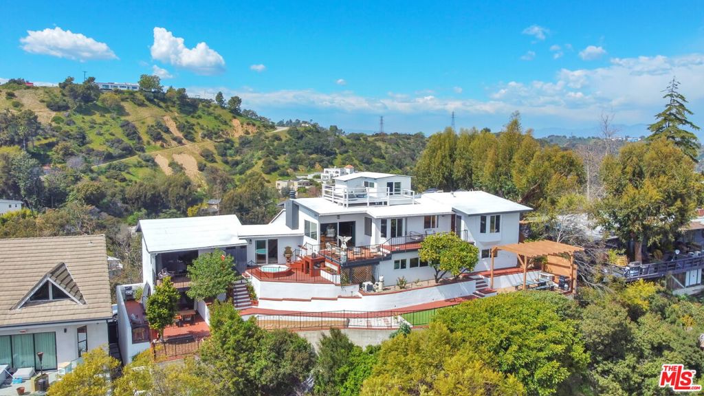 Perched atop its own promontory at the very top of Kew Drive (on a double lot), this one-of-a-kind Spanish estate offers unmatched privacy, jetliner views, and a rich creative legacy in the heart of Laurel Canyon. Lovingly named "Belladonna" and built in the 1920s, the property has hosted icons like Marilyn Monroe and is said to have inspired countless songs, films, and screenplays within its storied walls. With many thoughtful updates completed in 2023 including a brand-new roof, windows, and bathrooms, the 3 bed / 2 bath main residence features wood-beam ceilings, original architectural details, and sweeping views from nearly every room, stretching from the Hollywood Sign and Griffith Observatory to Downtown L.A., the ocean, and Catalina Island. An open, sunlit layout flows seamlessly to wraparound decks, an in-ground hot tub, and a backyard dining area shaded by mature fruit trees (pomelo, lemon, kumquat, tangerine). A separate 2 story, fully self contained, 1 bed / 1 bath guesthouse with soaring ceilings and private yard and balcony currently generates $4K/month in rental income, with potential for more. The property also includes a versatile bonus basement studio, separate hidden office, a spacious two-car garage, secure gated entry, and a rooftop deck with true 360 views, arguably the most iconic in Los Angeles. Whether you're seeking a creative sanctuary, income-producing retreat, or piece of Hollywood history, this is where legacy lives above the city lights.