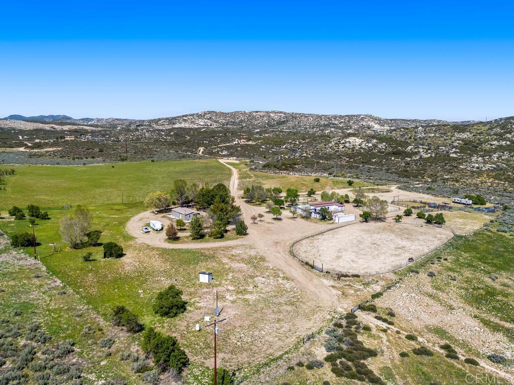 CW Ranch – A Rare Slice of Country Living! Discover a unique opportunity to own a 50-acre ranch in the tranquil backcountry of Pine Valley, just under an hour from downtown San Diego. CW Ranch offers a rare blend of privacy, accessibility, and endless potential for a variety of agricultural and rural endeavors. With vast, open spaces, a thoughtfully designed ranch infrastructure, and the freedom to cultivate your dream lifestyle, this property is perfect for those seeking a self-sustaining homestead, a small ranching operation, or a peaceful escape from city life. ~The property features a comfortable, upgraded 3-bedroom, 2-bath single-story ranch home with a functional open floor plan that includes abundant natural light and high ceilings. Situated privately on fully usable acreage, the home is meticulously maintained and ready for immediate enjoyment. ~CW Ranch is fully fenced and cross-fenced, with meandering walking paths, and shaded nooks that invite relaxation. A seasonal creek winds through the landscape, while mature trees and abundant wildlife—including quail and deer—create a peaceful, park-like setting. The property is ideal for horse lovers, with a 6-stall barn and an attached large workshop with dedicated 100A service, irrigated paddocks, working cattle pens, and two arenas. Newly painted outbuildings include a tack room, several multi-purpose sheds and two metal cargo containers providing ample space for storage. ~For agricultural enthusiasts, the property boasts rich bottomland soil, making it ideal for farming or ranching activities. The ranch operates sustainably with a private water well, ensuring efficient water management across the ranch, and a 22kW Generac propane generator for back-up power. The property also features full RV hookups (30A & 50A), and is prepared for future expansion, with a separate power meter already installed on an elevated knoll, offering incredible views of the ranch and the surrounding pristine landscape. This knoll is an ideal spot for a guest house or ADU, adding significant versatility to the property. ~Explore the surrounding area through countless hiking and riding trails, perfect for outdoor enthusiasts and nature lovers. Whether you want to create your dream homestead, grow an agricultural operation, or simply embrace a more grounded way of life, the ~CW Ranch offers the space, infrastructure, and freedom to make it happen. This property is offered with negotiable equipment. Come experience the lifestyle at CW Ranch for yourself!