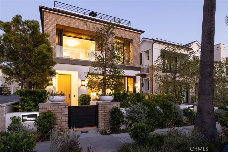 In one of Corona del Mar’s most coveted enclaves, this coastal retreat captures the essence of luxury village living—where curated interiors and seamless indoor-outdoor flow define every space. Completed in 2022, this front-unit residence offers approximately 1,761 square feet of refined living space with three bedrooms and three-and-a-half baths, just four blocks from the beach. A quintessential front patio sets the stage, featuring a built-in BBQ, gas fire pit, and accordion glass doors that open to a warm, inviting great room. Inside, European white oak flooring, abundant natural light, and a statement electric fireplace complete the space with warmth and style. A dedicated dining area connects the living space to a magazine-worthy kitchen, showcasing Miele cooktop and 8-burner range, Liebherr column fridge and freezer, hand-troweled plaster hood, waterfall-edge quartz island, and a striking stone backsplash. Further along, a main-level ensuite bedroom offers flexible use as a guest retreat or home office and opens to a peaceful rear courtyard. Upstairs, the primary suite is a private sanctuary with its own electric fireplace, glass sliding doors to a covered terrace, and a spa-inspired bath complete with dual quartz vanities, soaking tub, and walk-in shower. A secondary ensuite bedroom and full laundry room complete the upper level. Crowning the home, an expansive rooftop deck boasts panoramic views of the ocean, city lights, and iconic palms. Additional highlights include white oak interior doors, custom closet buildouts, Rocky Mountain hardware, and Control4 smart home automation. A one-car attached garage, plus carport, offers exceptional convenience—made even more rare by the privacy of having no homes behind the lot. Just steps from the iconic Goldenrod Footbridge and moments from local cafés, shops, and restaurants, this turnkey home represents a rare opportunity to enjoy the very best of coastal California living.