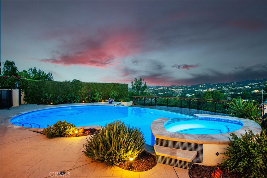 Perfectly positioned at the end of a serene cul-de-sac street, this gated oasis offers panoramic valley and mountain views, perfectly blending modern elegance with effortless California living. As you enter the double iron doors, you're greeted by an inviting foyer and fabulous layout flooded with natural light, accentuated by gleaming wood floors and breathtaking vistas. The expansive living room is anchored by a central fireplace and seamlessly flows into a stylish dining area—ideal for both intimate dinners and holiday entertaining. The spectacularly updated chef’s kitchen boasts quartz countertops, Wolf & SubZero appliances, custom cabinetry, and a spacious center island dining area with fabulous wine bar! Opening from the kitchen is the wonderful family/media retreat where you can enjoy your favorite movie or just gaze at the spectacular views. Featuring four generously sized bedrooms which include its luxurious primary suite with a patio, walk-in safe room closet, and a lavish en-suite bath with dual sink vanity, soaking tub, seamless glass shower and private commode. Each space is thoughtfully designed to maximize comfort and style, with curated finishes throughout. Step outside to your own personal sanctuary—lushly landscaped with multiple lounging areas, a sparkling infinity pool/spa, entertainers bar with outdoor kitchen, manicured grassy play area and plenty of space to unwind while taking in the magnificent valley panoramas. Whether you're entertaining under the stars or enjoying a quiet sunrise coffee, the backyard delivers a resort-like ambiance year-round. Additional highlights include an attached garage with direct access, sound system, and proximity to top-rated schools, hiking trails, and the vibrant dining and shopping scene of Ventura Blvd. Don’t miss this rare opportunity to own a beautifully updated Encino estate that combines privacy, tranquility, and unmatched views in one extraordinary offering.