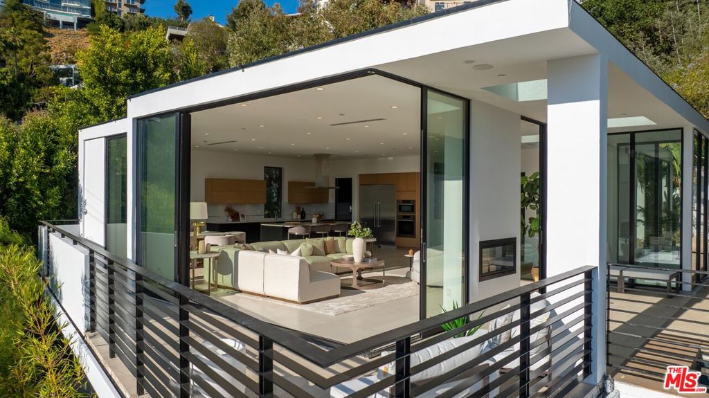 Priced to sell!!! Tucked away in the coveted Hollywood Hills, just moments from the iconic Sunset Strip, this contemporary oasis offers breathtaking city light and ocean views. A true luxury residence, this hillside retreat features custom doors, oak floors, soaring ceilings, and a private office located on the first floor with its own separate entrance. The property offers four bedrooms plus one office. The main level showcases a sophisticated open floor plan with sliding glass doors that create seamless indoor-outdoor living. The gourmet kitchen is a chef's dream, complete with a spacious center island, Miele appliances, and extensive cabinetry for ample storage. The second level includes two en suite bedrooms and a versatile en suite theater room that can also serve as an additional bedroom. The exquisite primary suite crowns the top floor, complete with a fireplace, dual custom closets, skylights, a lavish bath, and a double shower with private access to the backyard. Step outside to enjoy the pool, spa, and tranquil outdoor living spaces perfect for both relaxation and entertaining. An elevator offers convenient access from the garage to the top floor. Set in a coveted location among the serene hills, yet just moments from the very best of West Hollywood, Beverly Hills, and beyond - this home blends privacy, luxury, and unbeatable access to L.A.'s premier dining, shopping, and entertainment.