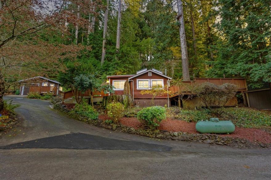 Arrive at your peaceful redwood retreat, a cozy cottage nestled among towering trees just minutes from Downtown Scotts Valley. Step onto the generous wraparound deck built from local redwood and feel life slow down as you sip morning coffee or unwind while the forest glows around you. The large driveway offers plenty of room for oversized vehicles, and the one car garage with workshop space gives you a place to tinker, create, or store gear. An attached studio adds an ideal spot for guests or a quiet workspace. Behind the home sits a charming garden cabin with a loft and electrical hookups, perfect for an artist studio or second workspace tucked away from the main cottage. The landscaping adds extra magic with mature maples, camellias, dogwood, and lush seasonal blooms that color the property year round. Inside, the home welcomes you with fresh paint, new counter tops, and thoughtful updates that keep its warm vintage charm. The spacious bedroom looks out onto a private patio surrounded by ferns and redwoods, creating a peaceful start or end to your day. With Highway 9 and 17 nearby, commuting is easy while the property still feels like a quiet forest escape. Only 15 minutes to Santa Cruz and 30 to Los Gatos. This is a place to slow down and feel at home.