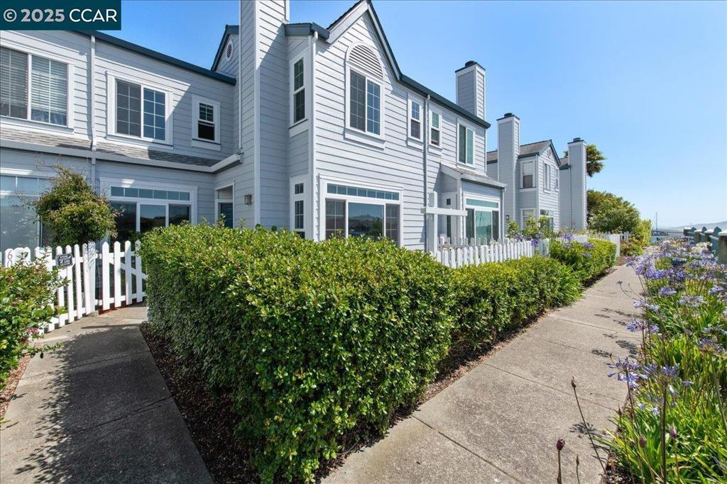 Come see what coastal living with a waterfront view is all about.   Start your day with a stroll along the Bay Trail, then take a 30-minute ferry ride to San Francisco—no Bay Bridge stress, just coffee and views.  This 2BR/2.5BA PUD townhome in Marina Bay blends coastal charm with modern comfort. A sunny patio with a white-picket-fence and two dedicated parking spaces offer privacy and convenience rarely found in a gated community.  Inside, light-filled spaces feature LVP floors, 9-ft ceilings, and a cozy fireplace. The kitchen has an open counter for bar stool seating and pass through to  dining room; great for relaxed gatherings.  Two ensuite bedrooms upstairs—both with vaulted ceilings and water views—provide peaceful retreats.  Low HOA dues, scenic paths, and marina access are right outside your door.  Life here feels like a getaway—every single day.