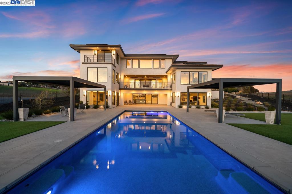 A majestic modern masterpiece awaits you at 7785 Laguna Heights, located in coveted Sunol. Located on a well-manicured 3.53 acres, this 9,826 SF elegant estate features 7 exquisite bedrooms with walk-in closets, 7 full luxurious bathrooms , 3 powder rooms, an elevator, natural light, premium heavy doors and a chef’s dream of a kitchen with Thermador appliances, including an induction cooktop, two dishwashers, and a mini fridge. Entertainment is a key part of life at 7785 Laguna Heights as it includes an amazing wine room with a glass enclosure, cooling unit, and a 600 plus bottle capacity, perfect for every connoisseur. Not to be missed, the in-ceiling speaker system throughout the house, including outdoor areas. The audio-visual equipment and cabinetry are integrated with Control4 technology. Step outside and be surrounded by the beauty of nature, along with infrared heaters on aluminum tiled balconies and patio, and a finished outdoor kitchen featuring a Lynx BBQ and two Bruster pergolas with louvres that open and provide sun protection. The salt water pool with spa has an automatic retractable cover and the outdoor fireplace is wired for TV above. Easy access to 680 freeway and major tech companies as well as minutes from downtown Pleasanton.