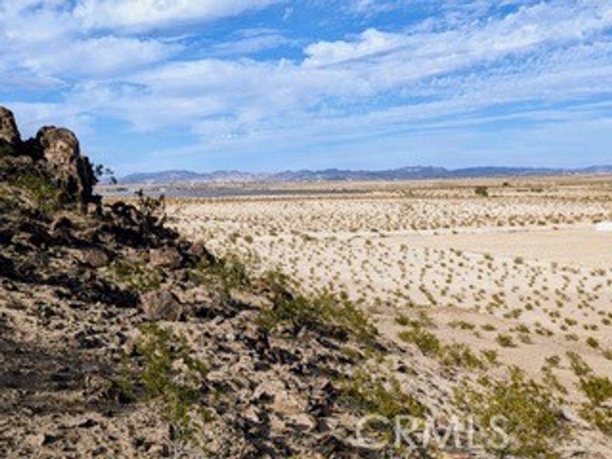 This stunning 10-acre parcel in the sought-after Copper Mountain East area of 29 Palms is an ideal opportunity for development. This gorgeous corner lot enjoys elevation, boulders and panoramic views, as well as already having a water meter on site. The seller has existing plans, initially approved by the City in early 2021, that will likely require re-approval due to the date. The parcel only requires the dedication of a small portion of the frontage for utilities to finalize the plans. The seller believes that with minor updates, approval and dedication can be completed efficiently with the help of an engineer. In addition, the survey, topographical map, and perc and mantle have all been completed and are available. The property is well-suited for a parcel split or a custom build. All relevant plans are available in electronic form for serious buyers to review. The seller has also explored the potential costs of building out the approved plans, estimating the overall investment for infrastructure and construction to be highly competitive for the area. This is a unique opportunity for a developer or buyer looking to create a custom living space in the beautiful desert landscape of 29 Palms. Owner will carry with 25% down.
