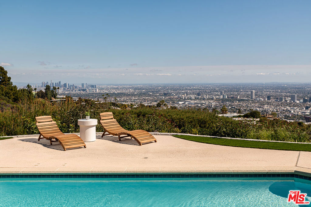 Rarely does the best representation of the original, iconic Trousdale style on perhaps the finest street in this storied enclave become available. With soaring high ceilings, head-on, unobstructed city views, and a location on nearly an acre on the preferred side of the street, 340 Trousdale Place is just that. Boasting 4 bedrooms, 5 and a half baths, a vast living room, and an enormous kitchen/breakfast/family great room, all opening to the pool and vistas, this residence is perfect for a connoisseur of fine mid-century architecture. Gated from the street, you enter from the large motor court through a second set of original filigree iron gates at the center courtyard then into the home's luxurious rooms with captivating scale. A private primary wing features rare double baths, a dressing area, a wood-burning fireplace, and sliding floor-to-ceiling glass doors flowing to the pool and city views. Updated while preserving the classic, original elan, this truly is a modernist gem.