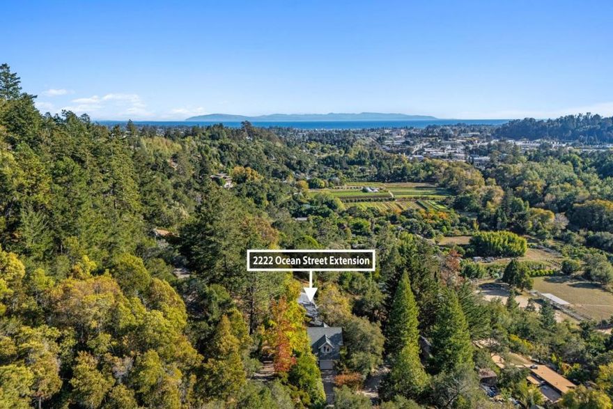 A rare opportunity to enjoy close-in country living just moments from downtown. Nestled above the picturesque San Lorenzo River, this private 1.2-acre sanctuary offers an effortless connection to nature while remaining minutes from every amenity. Gardens, mature trees, & an orchard frame this serene setting, enhanced by expansive decking, a terraced lawn, & a spa area designed for relaxation & entertaining. Panoramic views stretch across the valley to the town below & out to the shimmering bay & mountains beyond. The custom contemporary Craftsman residence showcases vaulted ceilings, skylights, & perfectly positioned windows that capture light & frame the surrounding landscape. The open-concept main level features a kitchen overlooking the dining & living spaces, centered around a fireplace & walls of glass that invite the outdoors in. The lower level has 2 spacious suites each with a private entrance, while two additional bedrooms & a full bath complete the home's thoughtful layout. A detached 2-story garage adds versatility with 2 large finished rooms ideal for an executive office, artist studio, or fitness space. Two driveways & additional parking ensure effortless access. Powered by a solar panel system, this estate blends timeless craftsmanship with modern sustainability.