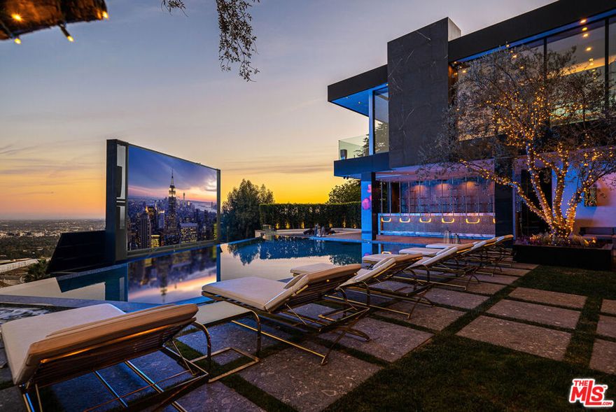 Seller accepts crypto! Experience the pinnacle of lavish splendor and quiet comfort at La Fin, or The End, aptly named as the ultimate, final example of modern decadence and refinement; the be-all and end-all experience in one of the world's most famous and exclusive enclaves. Sited on a two-acre parcel, this magnificent residence offers 12 spacious bedrooms, 17 bathrooms, remarkable amenities, and brilliant panoramic views of Los Angeles. Just beyond the gated motor court, proceed down to the oversized glass entryway to one of the most beautiful and opulent homes the globe over. A spiral staircase surrounds a stunning 44-foot chandelier made of 55,000 crystals, a showstopping centerpiece yet just one of the impressive custom lighting sculptures throughout the home. The main level features a custom stone bar that flows into the formal living area with a massive hand-carved stone latticework fireplace. All furniture was custom-made for La Fin by Italian luxury brand La Contessina. Motorized Fleetwood pocket doors open to the infinity-edge pool with a striking 23-foot LED screen that rises at the touch of a button and a 30-person lounge area with fire pit. The lower level provides a 6,000-square-foot entertainment area with lofty 18-foot ceilings, custom bar, commercial-grade catering facilities, 1,000-bottle wine cellar, cigar lounge, ice-cold vodka tasting room, and a jaw-dropping automated six-car vehicle elevator display. Additional amenities on the lower level include an outdoor lounge area, luxury fitness center with rock climbing wall, spa, steam room with backlit onyx, massage room, and sound-proof cinema. The second level features a grand primary suite with Italian hand-crafted floor-to-ceiling oak cladding, lounge area, coffee bar, spa-like bathroom with Calacatta Gold marble, massive 100-square-foot shower, solid marble vanity, dual showroom-style walk-in closets, and private wraparound balcony with sweeping views, spa, fire pit, and TV. The rooftop deck offers additional outdoor/entertainment space with built-in seating, fire table, video screen, elevated spa, and even more incredible vistas. Staff residences and a detached guest suite offer ample space. Fingerprint technology and security command center provide the utmost privacy and safety. The meticulously designed and curated La Fin is a once-in-a-lifetime Bel Air estate that can only be admired but never replicated.