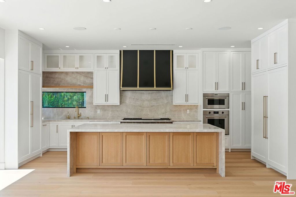 Prime Beverly Hills Flats Masterpiece. Single-Level Luxury with Guest House. Gated. Private. In the heart of Beverly Hills West-End Flats, this newly rebuilt home offers the rare combination of single-level living and modern elegance. With soaring high ceilings, an open concept floor plan, and thoughtfully integrated smart features, the home blends comfort, privacy, and sophistication. The main residence is anchored by a dramatic living and dining area that flows seamlessly into a show kitchen with top-of-the-line finishes and appliances, and a secondary back kitchen, ideal for entertaining and catering with ease. Walls of glass bring in abundant natural light while connecting every space to the outdoors. A versatile bonus room upstairs provides the perfect retreat for an office, studio, or a guest room. Smart living is at your fingertips with features accessible directly from your phone including face recognition entry, remote gate access, and a sound system with speakers throughout. Outdoors, lush landscaping frames the spectacular pool and creates a private resort setting. A separate guest house complete with full kitchen, bathroom, and views overlooking the pool offers exceptional accommodations for family, guests, or staff. With its balance of modern design, flexible living spaces, and a coveted Beverly Hills location.