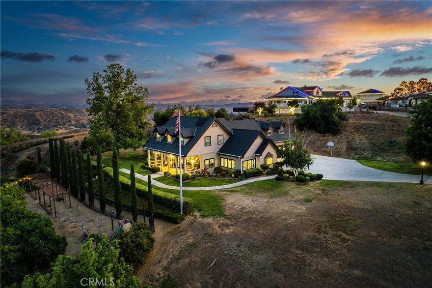 Welcome to this stunning Cape Cod-style estate nestled in the prestigious hills of Redlands, offering nearly 3 acres of privacy, panoramic mountain and canyon views, and incredible indoor-outdoor living. With over 130 fruit, citrus, avocado, olive, and pecan trees, plus raised garden beds, this home is ideal for those seeking a self-sustaining lifestyle. A lower orchard area with a stage and seating creates a unique venue-ready space for events, gatherings, or peaceful retreats. Inside, the home offers 3,431 sqft (plus an additional 600 sqft loft with a theater and bonus room), featuring dual primary suites on both levels. The heart of the home is the dream gourmet kitchen, a true chef’s haven, designed with stone countertops, custom cabinetry, luxury stainless steel appliance (Subzero Fridge, Wolf Ovens, Viking Stove and warming drawer), and a massive center island perfect for entertaining, prepping, or gathering around with loved ones. Its open layout flows seamlessly into the main living area, creating a warm and welcoming space. You’ll also find rich hickory hardwood floors, tile bathrooms, and an abundance of natural light throughout. Step outside to your private oasis featuring an in-ground pool and spa, brick wood-fired pizza oven, and multiple patios that capture the breathtaking views. Additional highlights include fully owned solar panels, three Tesla Powerwall batteries, eight water shares, a 3-car garage, and extended driveway parking. Located in the sought after Redlands Community, this one-of-a-kind estate offers luxury, sustainability, and space all in one breathtaking package. Don't miss your chance to own one of Redlands’ most iconic homes.
