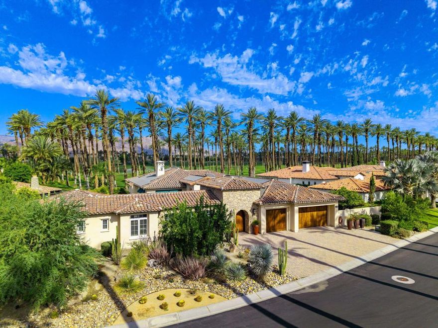 Experience the pinnacle of resort-style country club living at 56985 Village Drive, located in the highly sought-after Palms Country Club. This fully furnished, European Chateau-inspired estate offers 4 bedrooms, 4.5 bathrooms, and a private casita with its own entrance, kitchenette, dining, living, office area, bedroom, and spa-like bathroom with soaking tub, ideal for guests, extended family, or long-term visitors. Every detail of this home has been designed for comfort, elegance, and entertaining. Enter through a monumental private wooden gate into a grand courtyard featuring a central fountain, setting the tone for a residence that blends sophistication with timeless charm. Inside, the formal entryway opens to a formal living room with a billiards table and double-sided fireplace. To the right, a formal dining room, and off the kitchen, the breakfast room which offers expansive windows overlooking the golf course, offering stunning views of the greens, mountains, and palm trees. The chef's kitchen is a culinary dream, featuring a Sub-Zero refrigerator, commercial-grade stainless steel appliances, dual sinks, an eat-up island, and abundant custom built-ins. The residence also includes a large wet bar with wine fridge, perfect for entertaining family and friends. The primary suite serves as a private retreat, with a spa-like bathroom complete with dual vanities, soaking tub, shower, and a generous walk-in closet. Two additional bedrooms provide ample space, while multiple skylights, custom shutters, and ceiling fans throughout the home create an atmosphere of elegance and comfort. A spacious laundry room and 3-car garage, including room for a golf cart, add convenience and practicality. Step outside to a backyard that opens directly onto the golf course, surrounded by mature, lush landscaping. Stone pavers guide you through multiple entertaining areas, including a large covered patio with cathedral ceilings and ceiling fans, and an outdoor built-in BBQ. The pool area is a showstopper, with a large baja shelf, a river-style water feature that wraps around the property, and a waterfall spa. This estate provides seamless access to La Quinta's premier country club amenities, including a lively social calendar, clubhouse, dining, shopping, and nearby equestrian venues, polo fields, and tennis garden. Designed for those who desire luxury, privacy, and an elevated lifestyle, 56985 Village Drive is the ultimate combination of sophistication and desert charm.