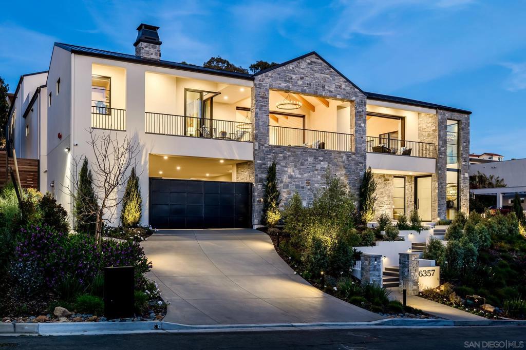 Standing proud above a quiet drive, this dream home emanates the grandeur of a European castle juxtaposed with an airy farmhouse. Winding through the manicured, modern garden one arrives at the oversized, pivot door entrance. The cool limestone foyer and art hall leaves gracious room to display a curated collection. Leading to the central living spaces is a series of floating oak steps with pin metal handrails casting sculptural shadows. Arriving at the main level reveals a series of illuminated living spaces. A warm wooden kitchen surrounds two generously sized islands. Each detail, from the custom Le Cornue stove fabricated for this home, to the skylights between the wood beams, shows the level of thought and detail in this 8,013-SF home. The luxurious primary suite and additional ensuites are exquisitely appointed with the finest finishes. Exterior spaces, which seamlessly integrate with the indoors, reveal a yard unlike any other, complete with pool and spa, pickleball court, lush green areas, detached guest suite, gym, and more. Each space on the property is attentively designed to maximize privacy, engaging views, and individual comfort. Outdoor living spaces on the front balcony views the western setting sun to the white water in Point Loma. Aligned with the kitchen is a cozy outdoor dining area with brick BBQ and fireplace. The intimate back yard has the privacy desired to enjoy the infinity edge pool, sun lounging space, and generous lawn. Guests can feel a welcome part of the family in the two-story guesthouse. Finished in the highest quality materials of the main residence, it has a compact complete kitchen, separate living room and bedroom. More entertaining areas throughout the yard include a large custom fire pit near a pickleball court. Whether entering from the interior living spaces or exterior private patio, the primary suite has been designed to meet every desire including a Venetian plaster fireplace, vaulted wood beam ceiling and ocean view. Separate custom closets, built-in cabinetry, and an additional washer/ dryer make daily dressing a breeze. The grand scale bathroom evokes a spa feel with natural light, cedar ceilings, limestone double shower, soaking tub, all fitted with soft brass accents. From the primary bath is a private patio with views to the private patio and gorgeous backyard. The home gym features full wall mirrors, water bottle filler, lockers, and steam shower. An additional mini suite is located on the lower level near the dual washer and dryer laundry room, elevator, and enclosed motor court. Light bounces through the entire home with skylights, bridge walk, and windows custom sized for each space. Soft oak, limestone, brick, and quarried stone all enhance the tactile experience of a modern home with traditional accents.