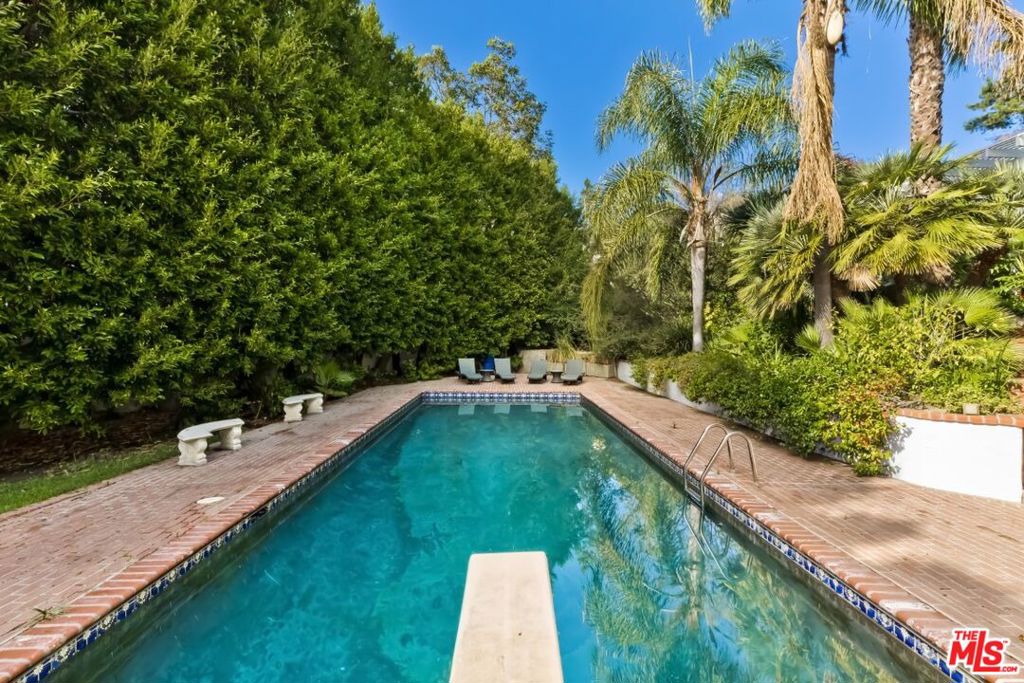 A rare opportunity to own 4 parcels that make up over 2 acres of land with amazing privacy. Limitless potential to create a new estate or enjoy the beautiful Traditional 5,300+ sq ft home. Upon entering the driveway, you leave the city behind as nature surrounds you. The circular courtyard welcomes you and offers ample parking in addition to a 3-car garage. Beyond the gates is a lush oasis-like setting created over decades. Included are several fruit trees, an expansive lawn, 20+ ft tall perimeter hedge, and a massive ficus tree in the center near the large swimming pool with original diving board, as well as a delightful treehouse. A magical path lures you to the 1930's home (originally belonging to actress Deanna Durbin) that has undergone considerable renovations. Classic and beautiful entry opens to a gracious living room with vaulted ceilings and a large fireplace. The adjacent family room is bright and spacious, and both rooms boast several sets of French doors that open to the front veranda. Large, rustic center-island kitchen with dining area and walk-in pantry open to the back deck with spa. This side provides a separate guest/in-law/nanny suite. The home also enjoys a romantic primary suite - with spa-like bath and 2 walk-in closets, additional en suite, a jack & jill, plus a den/office. Timeless design and quality with beautiful custom wood work, solid walnut hardwood floors and an abundance of storage throughout. Don't miss this once in a lifetime property! Exclusions: Tesla charger, art wall in guest suite, washer/dryer, several pots, plants & trees around property. Parcels include both Tract 9300 and Palisair HOA.