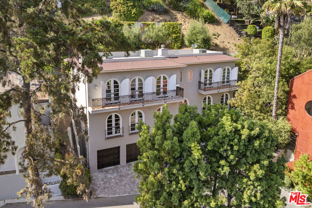 Built in 2005, this European-inspired villa pairs Old World charm with all the modern upgrades. Think dramatic 10-foot ceilings, arched French doors that flood the living spaces with southern light, and custom details everywhere from custom paneled walls, Venetian Plaster accents, and built-in bookcases to the dark hardwood floors underfoot. The home is fully furnished with high-end designer pieces and comes move-in ready, down to the espresso bar in the kitchen. Speaking of, the chef's kitchen is equipped with an industrial gas range, a huge center island, and everything you need to host in style. Just outside, ivy-covered walls frame a private outdoor patio with built-in seating, a barbecue, and a plunge pool/spa that flips effortlessly from summer cooldown to cozy evening soak. Upstairs, the primary suite is a true retreat with its own fireplace, spa-like bath (soaking tub + oversized shower), massive walk-in closet, and custom wardrobes. French doors open to an expansive balcony overlooking lush canyon views. Secondary bedrooms are spacious and all include an en suite bath. Extras include: a first-floor guest suite/in-law option, three-car garage plus driveway parking for three more, central air and heat, a full security system with cameras, a library/media room with paneled walls and a separate family room off the kitchen. Tucked into a quiet pocket of the Hollywood Hills, you're close to Bronson Canyon trails, Los Feliz Village and minutes from the city, but it feels like you've been dropped into Lecce.