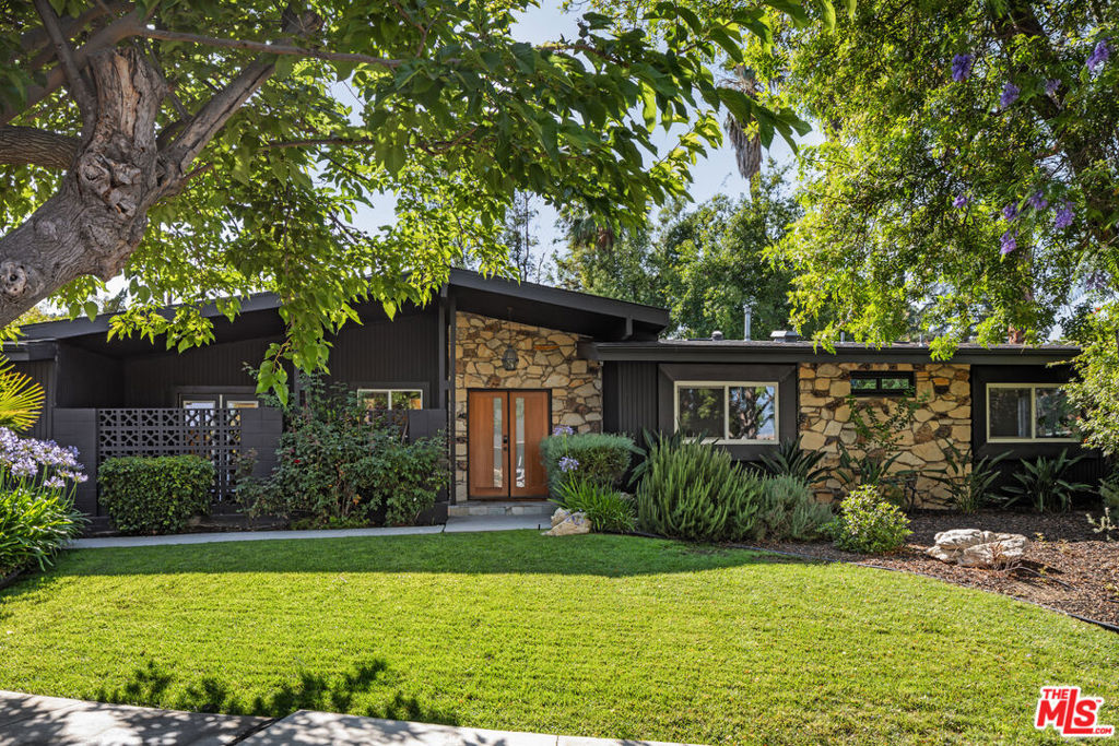 Tucked away on a tranquil, tree-lined cul-de-sac, this stunningly reimagined Charles Du Bois Mid-Century home offers an elevated living experience in one of Woodland Hills' most coveted pockets. Blending timeless mid-century architecture with modern luxury, the home has been thoughtfully updated with high-end finishes and inspired design choices throughout. Ideally located near top-rated schools, The Village, The Commons, and a vibrant collection of premier restaurants, this retreat places you in the heart of it all while still feeling worlds away. Inside, natural light pours into an expansive open-concept layout framed by dramatic glass walls and a striking double-sided fireplace. The living spaces flow effortlessly into the lush backyard, where a custom-designed pool and spa anchor a resort-style oasis, complete with a sleek gazebo, built-in BBQ, and deck with an outdoor fireplace, perfect for entertaining year-round. At the center of the home, the chef's kitchen stuns with walnut cabinetry, concrete slab countertops, and seamless integration into the dining area featuring a cozy fireplace, custom dry bar, and oversized sliders that open to the private yard.Hidden behind discreet paneling, a bespoke speakeasy offers the perfect spot for intimate evenings or spirited gatherings. The primary suite impresses with soaring ceilings, a fireplace, a boutique-inspired walk-in closet, and a spa-like bath that redefines relaxation. Step outside to a beautifully designed pergola and alfresco dining area creating a captivating backdrop for evenings under the stars. From its welcoming, tree-framed entry to the serene, Zen-style grounds, this property captures the essence of California indoor-outdoor living at its finest.